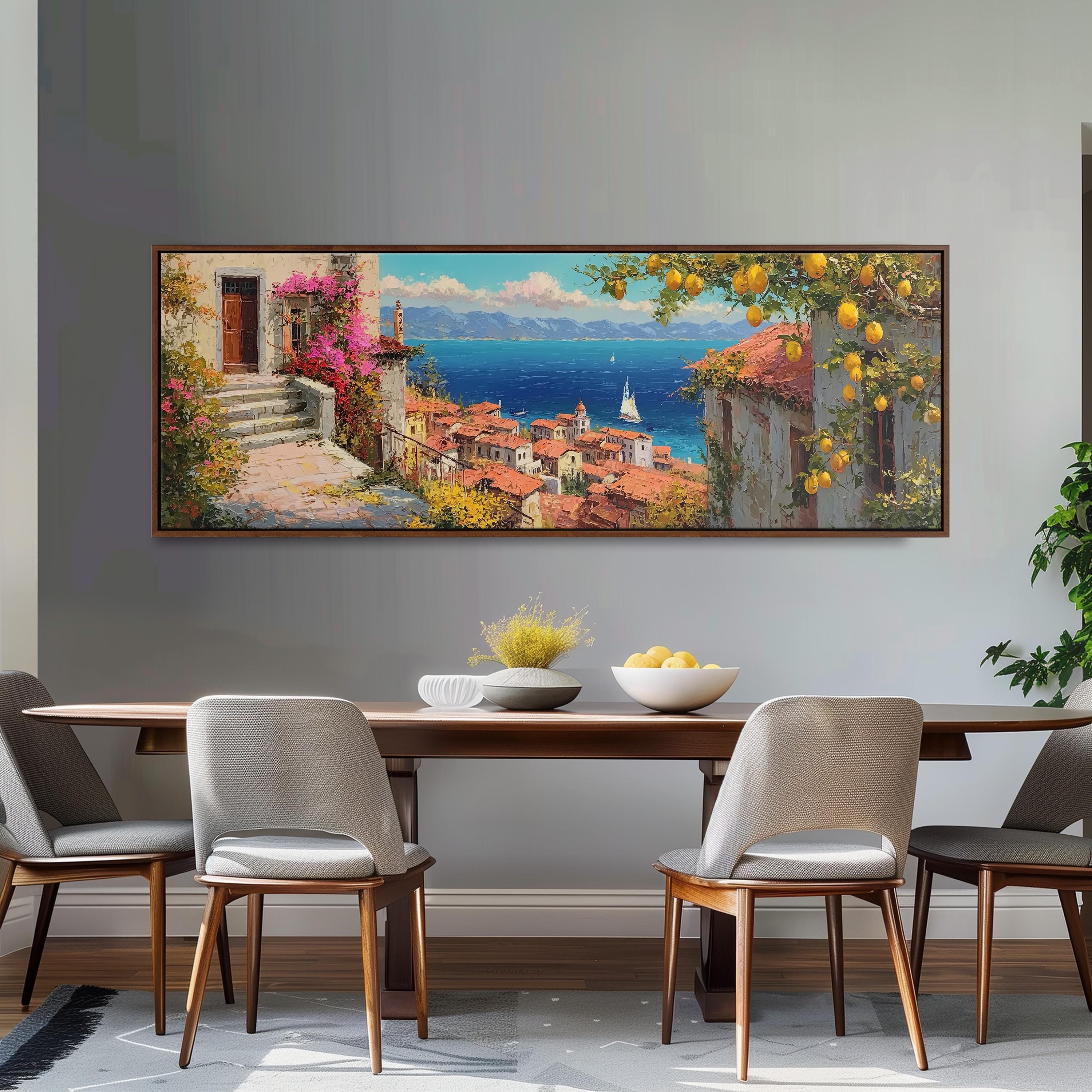 a large painting of a coastal town with a view of the sea, hanging on a wall above a wooden dining table with four chairs.