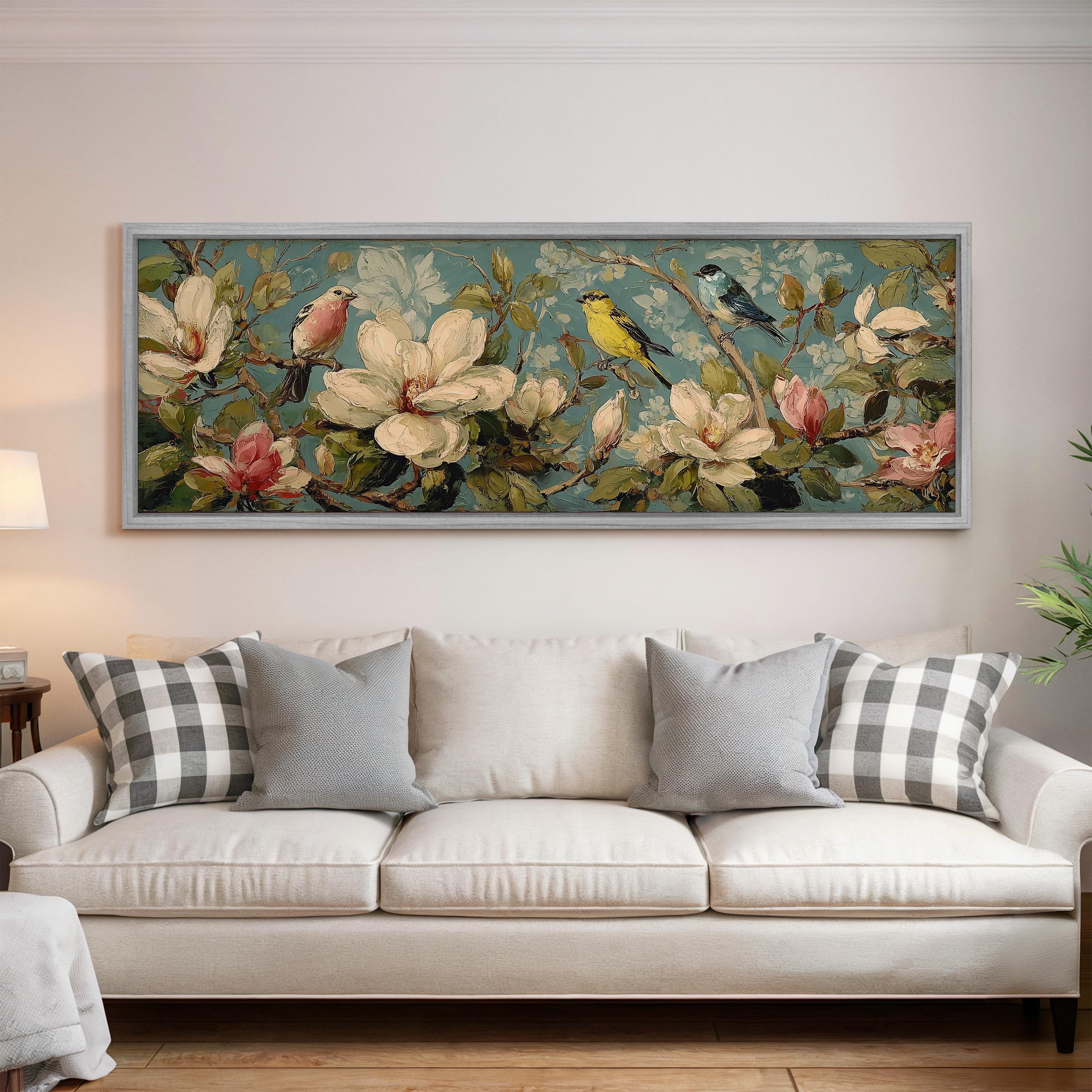 a large floral painting hanging on a wall above a white sofa with gray and white plaid throw pillows.