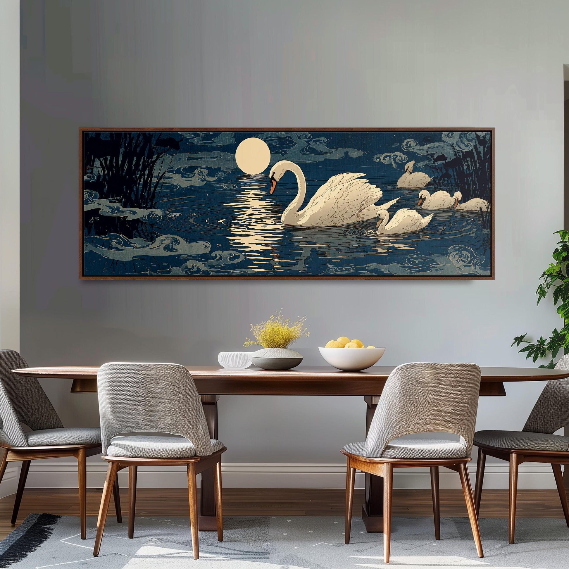 a large painting of a swan swimming on a lake at night, with a full moon and clouds in the background. The painting is hung on a wall above a wooden dining table with four chairs around it. The table is set with a bowl of fruit and a vase of flowers, creating a cozy and inviting atmosphere.