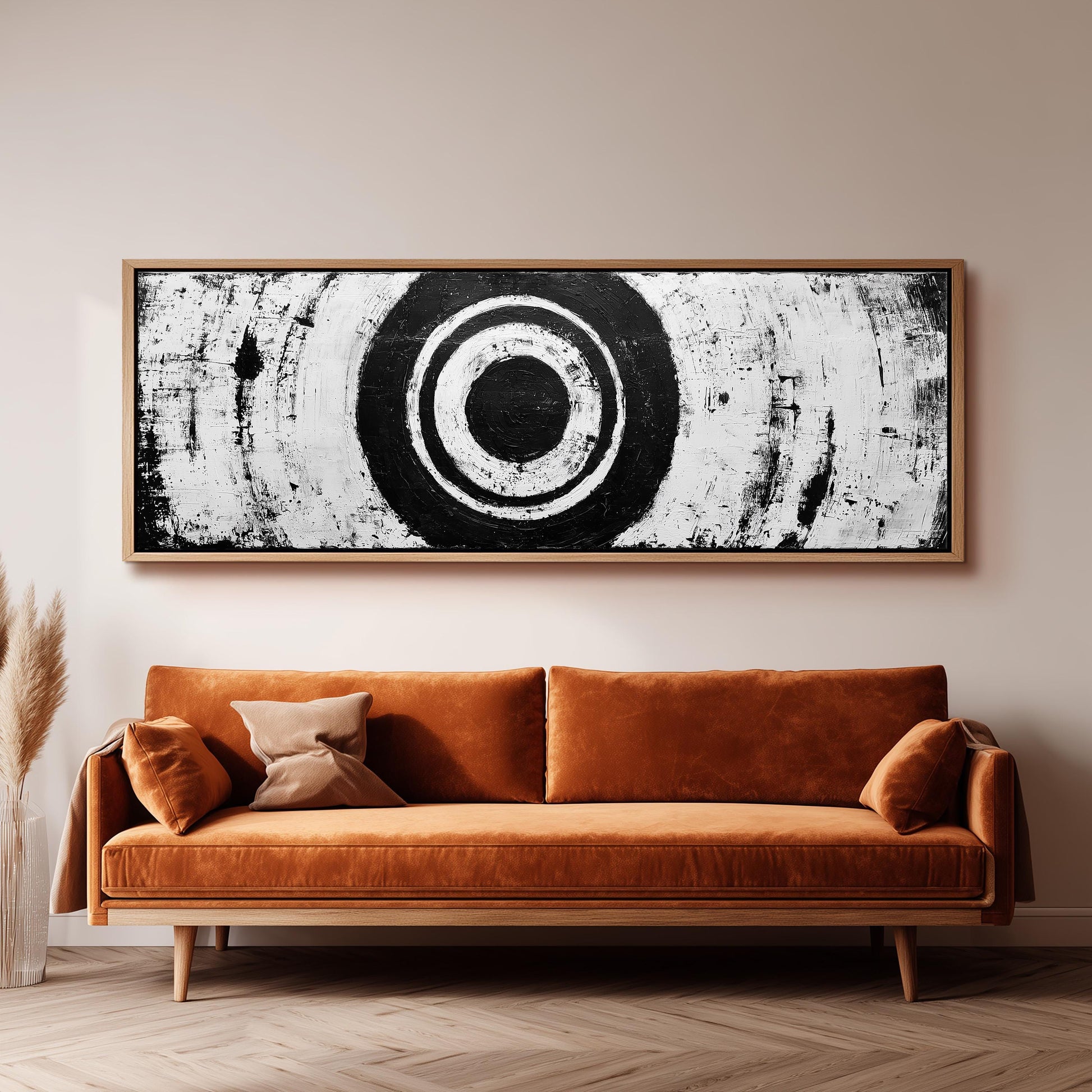 a large black and white abstract painting hanging on a wall above a brown sofa.