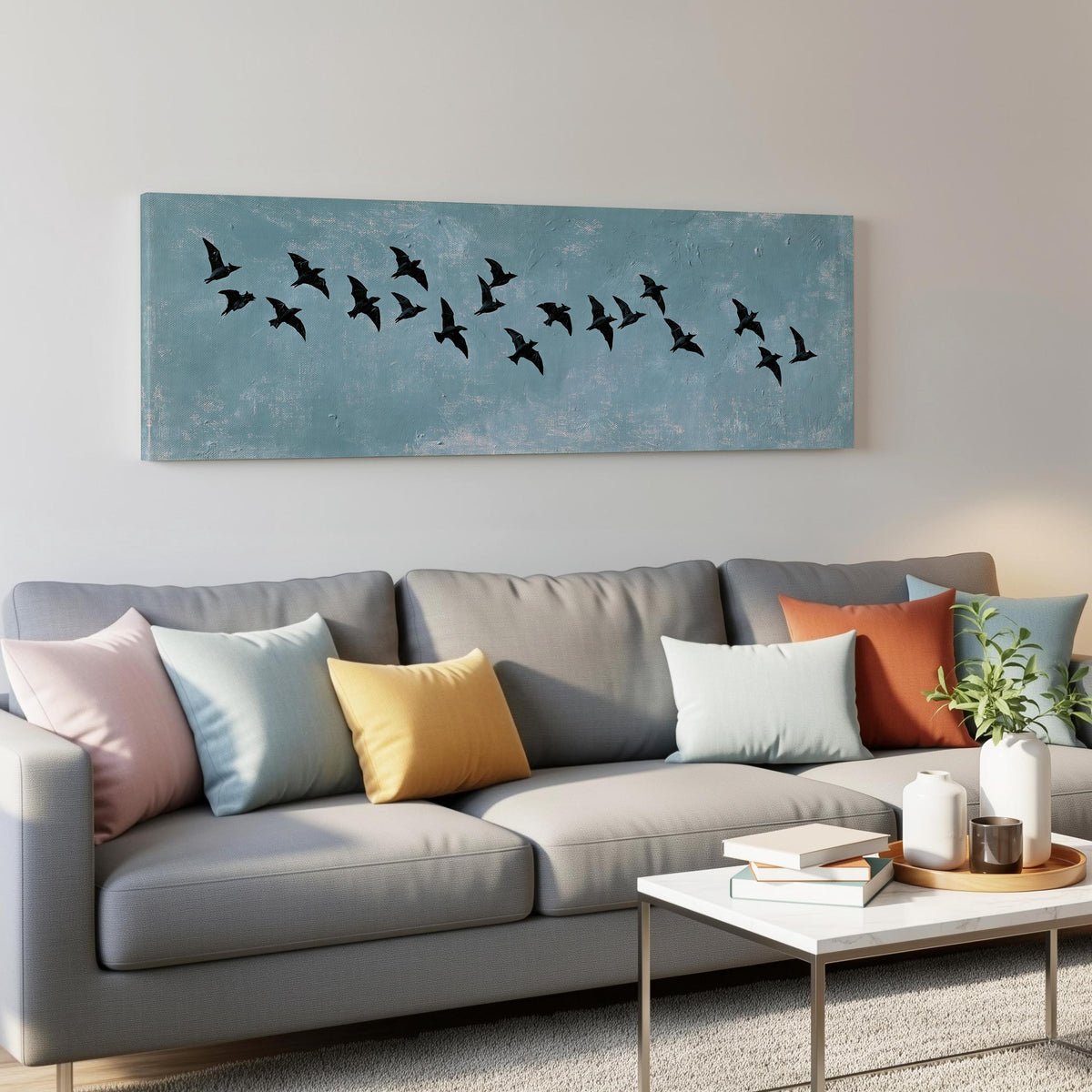 Flock of black birds on a teal sky panoramic canvas print above a grey sofa in a living room