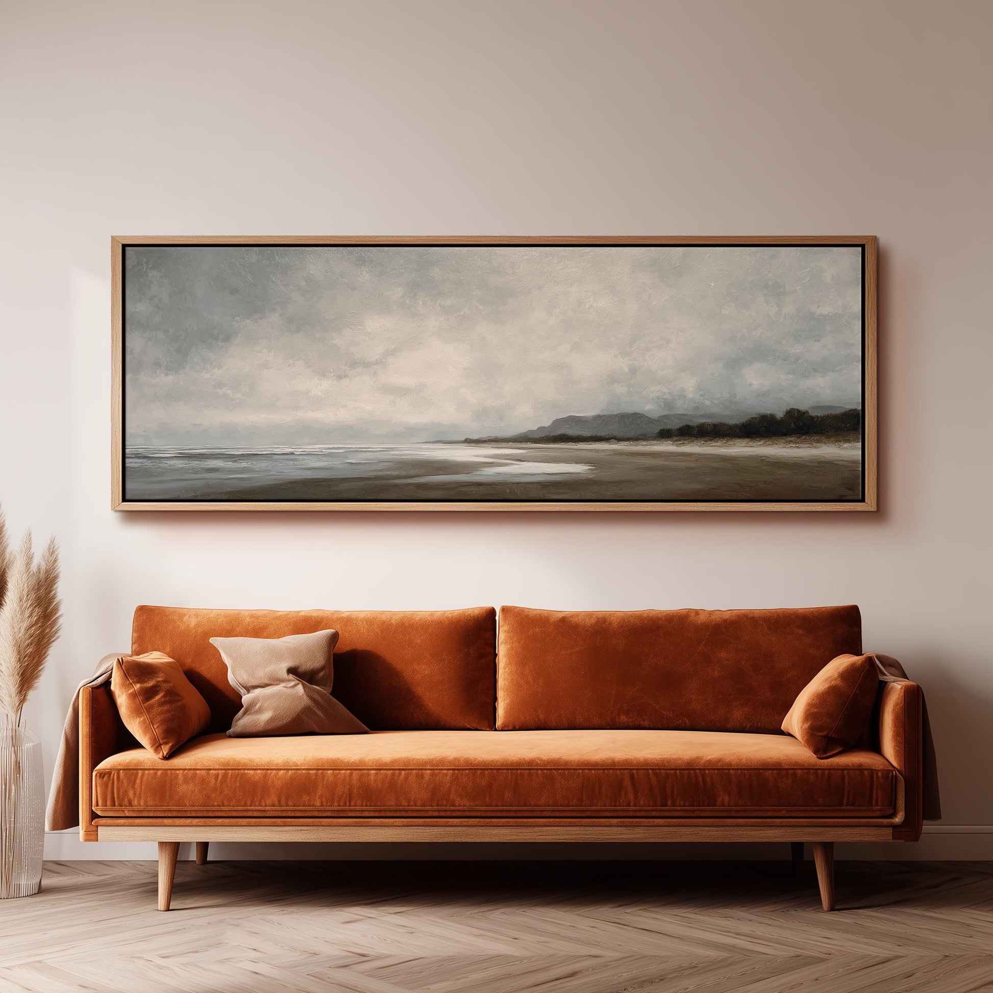 a large, rectangular painting hanging on a wall above a brown sofa with orange cushions.