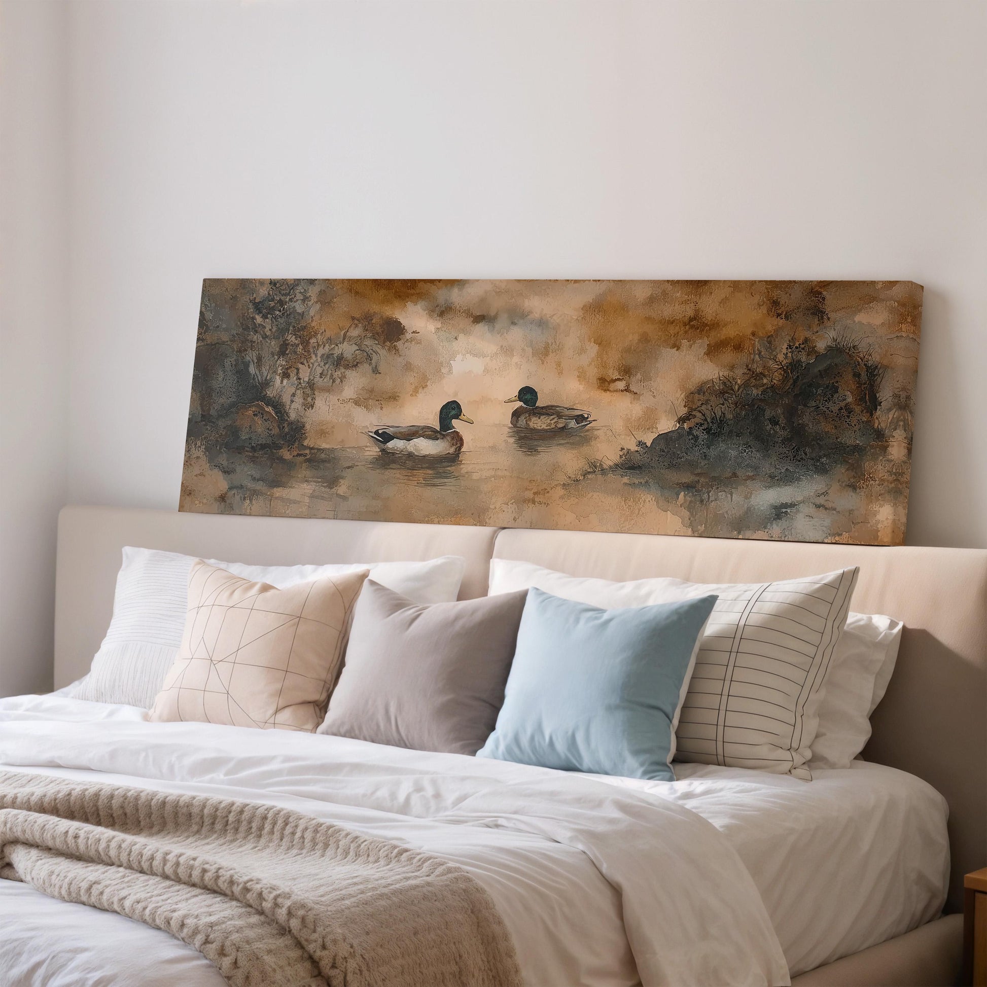 a large painting of ducks on a bed with a white headboard and a beige comforter.
