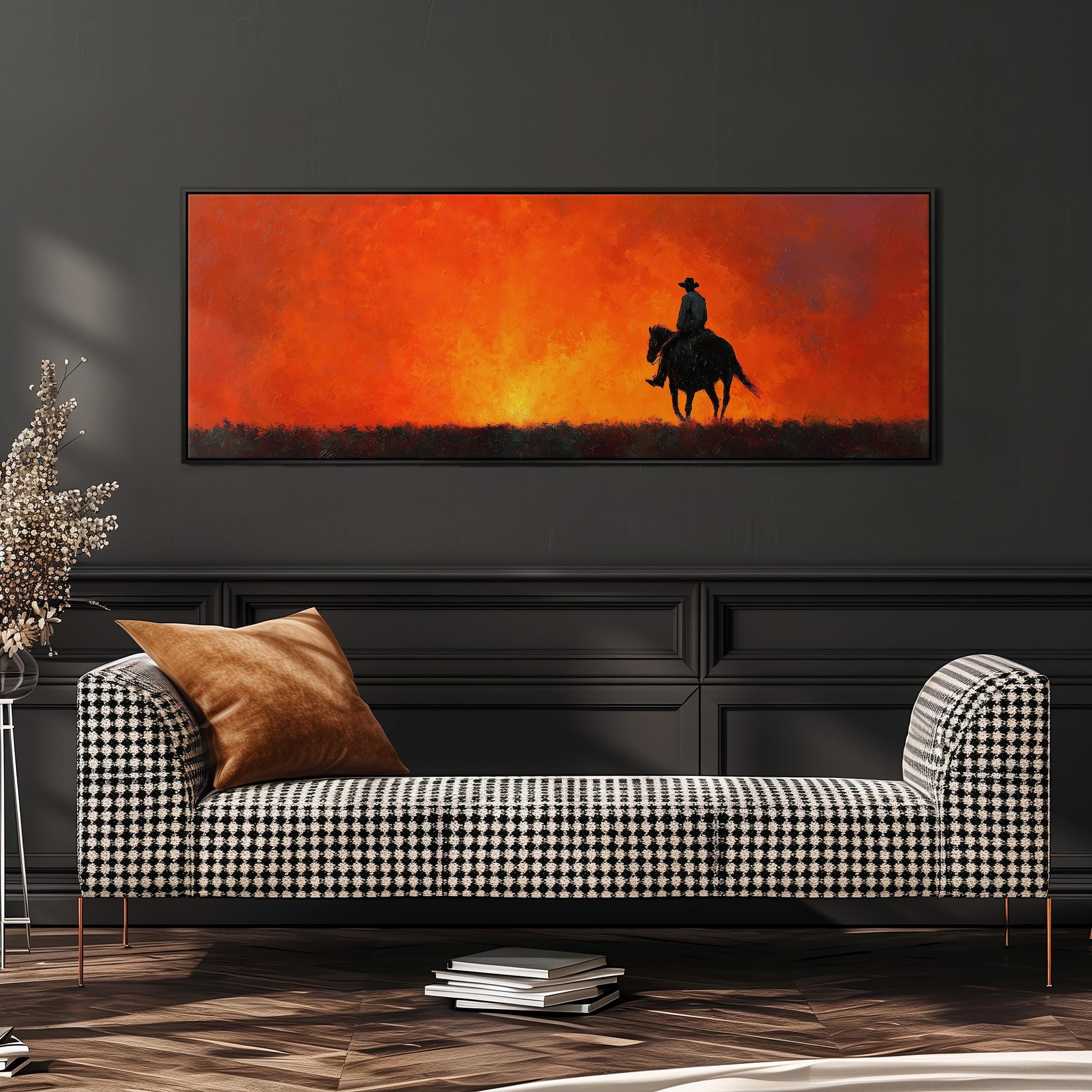 a large painting of a cowboy riding a horse against a backdrop of a sunset. The painting is displayed on a wall above a black and white checkered sofa, which is positioned in front of a bookshelf.