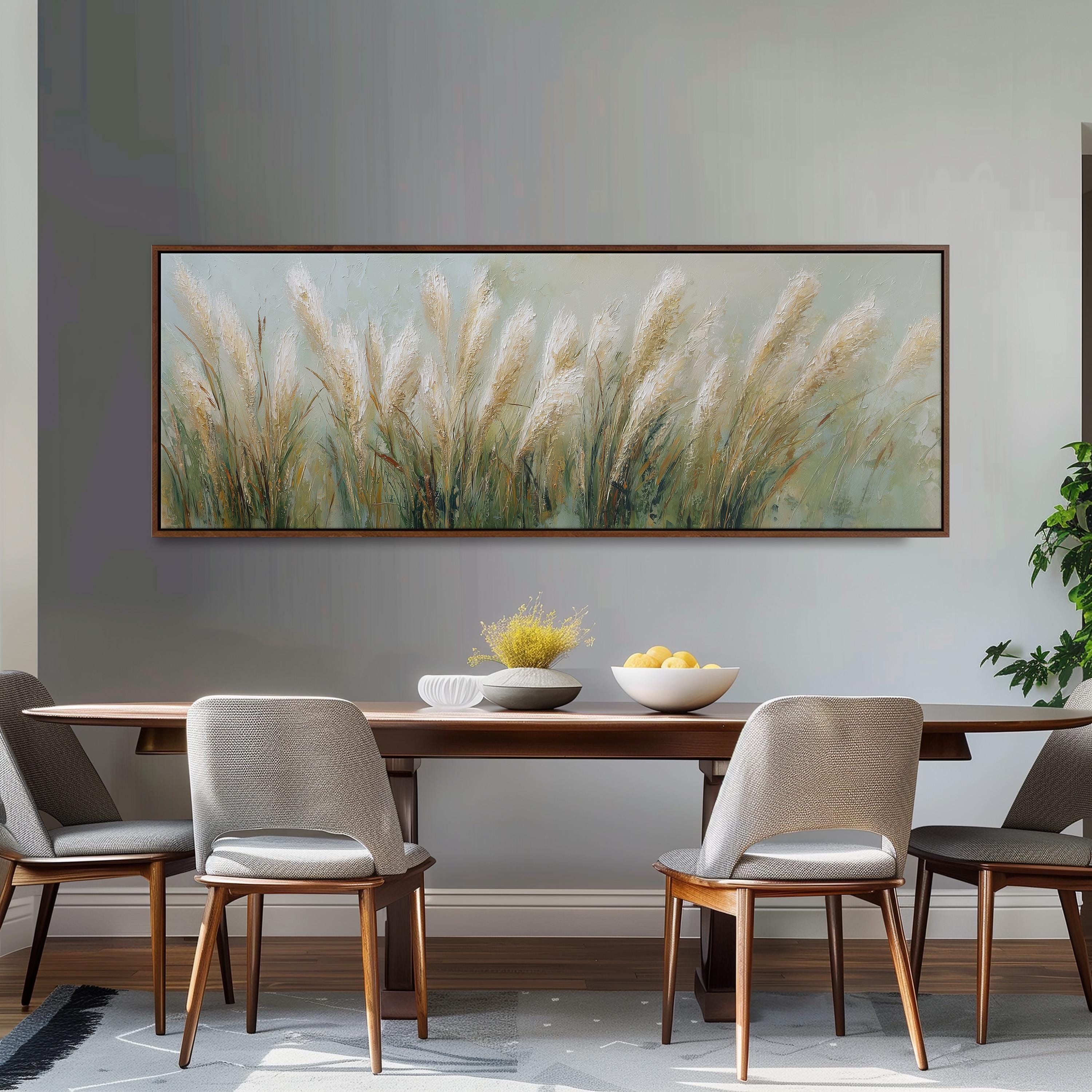 a dining room with a large painting of tall grass hanging on the wall above a wooden dining table with four chairs. The table is set with a bowl of fruit and a vase of flowers, creating a cozy and inviting atmosphere.