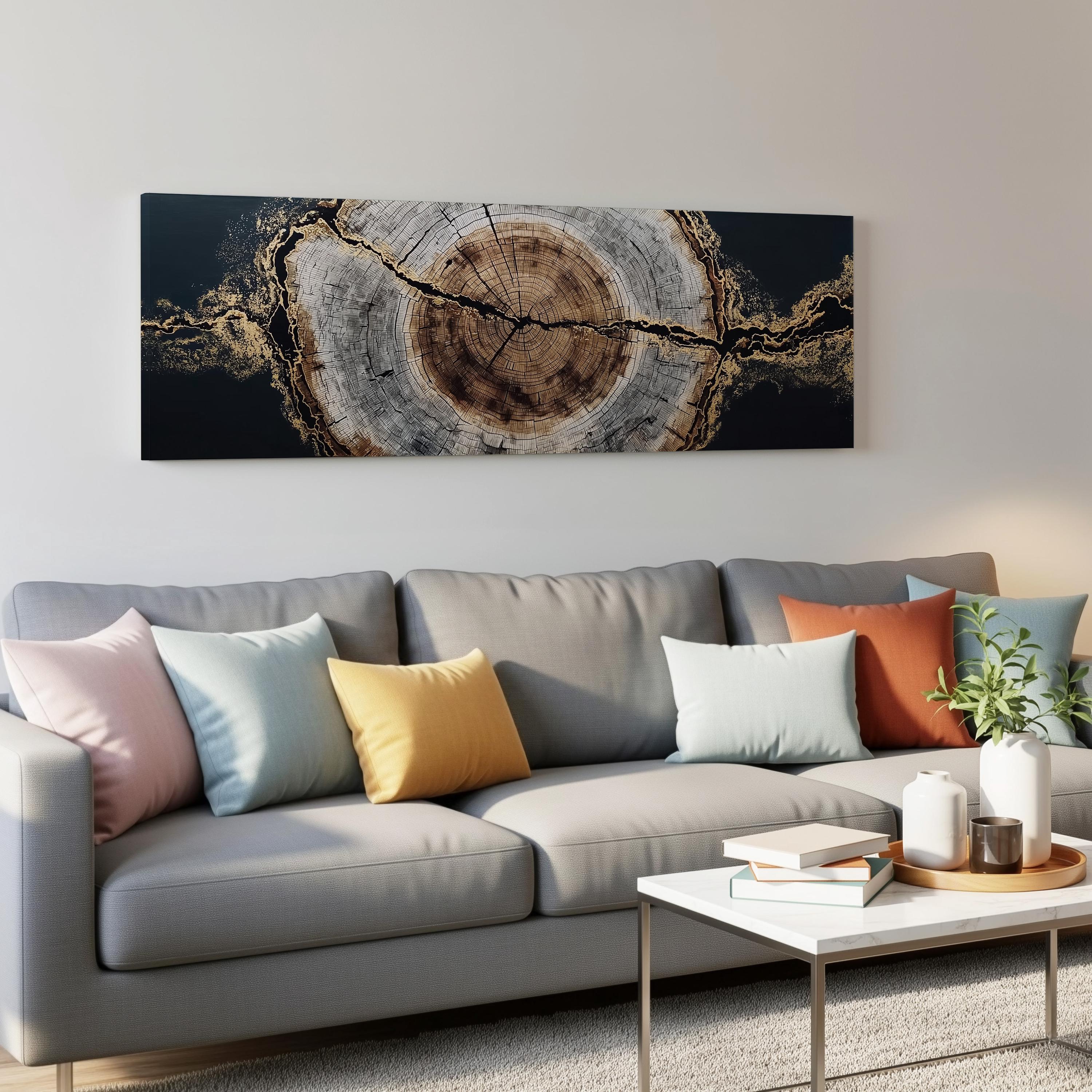 a modern living room with a gray sofa adorned with colorful throw pillows. Above the sofa, there is a large black and gold abstract painting hanging on the wall. In front of the sofa, there is a white coffee table with a stack of books and a small plant.