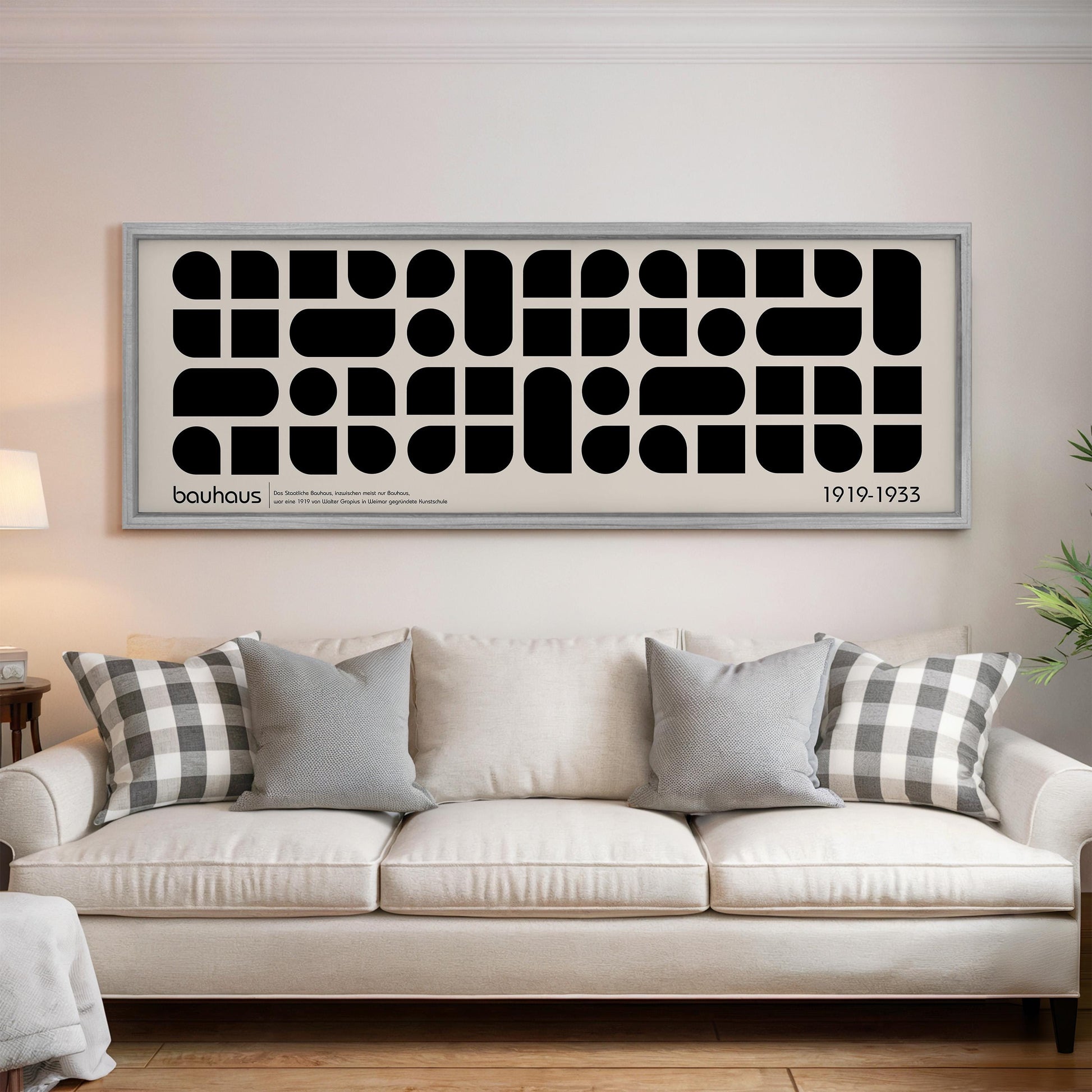 a large black and white abstract art piece hanging on a wall above a white couch with gray and white throw pillows.
