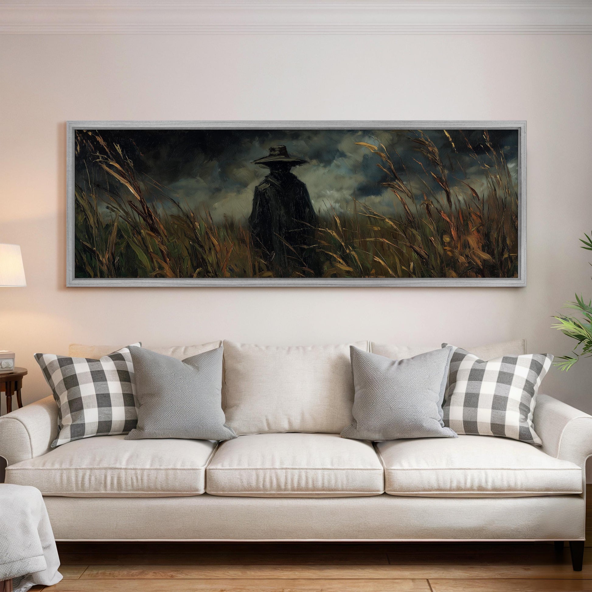 a large painting of a person in a hat standing in a field of tall grass, hanging on a wall above a white couch with patterned throw pillows.
