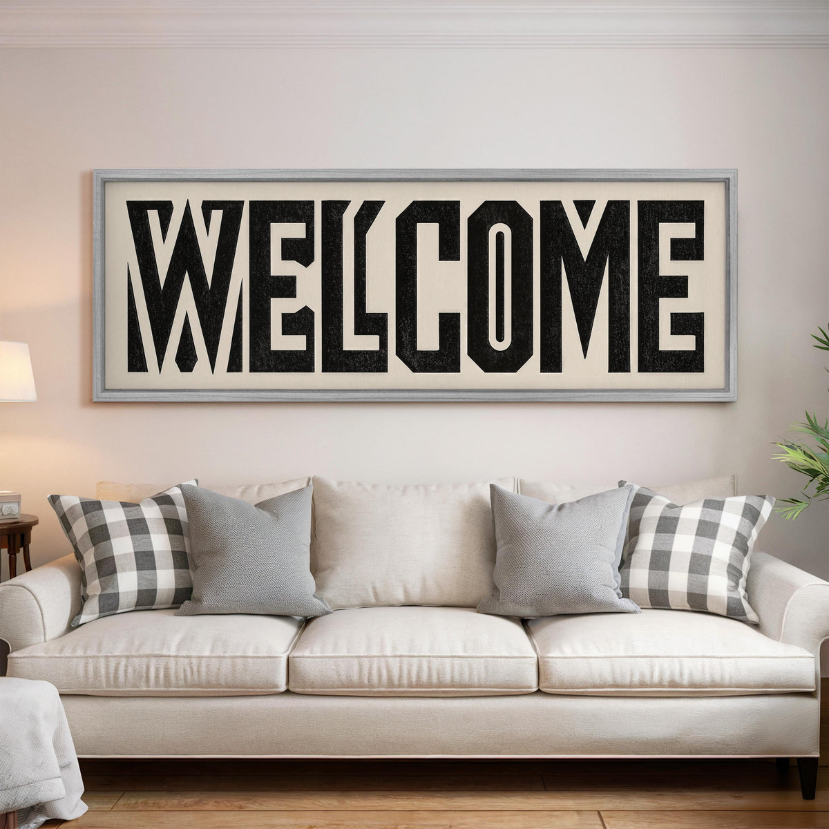 Bold welcome block letters panoramic canvas print above a white sofa in a bright living room