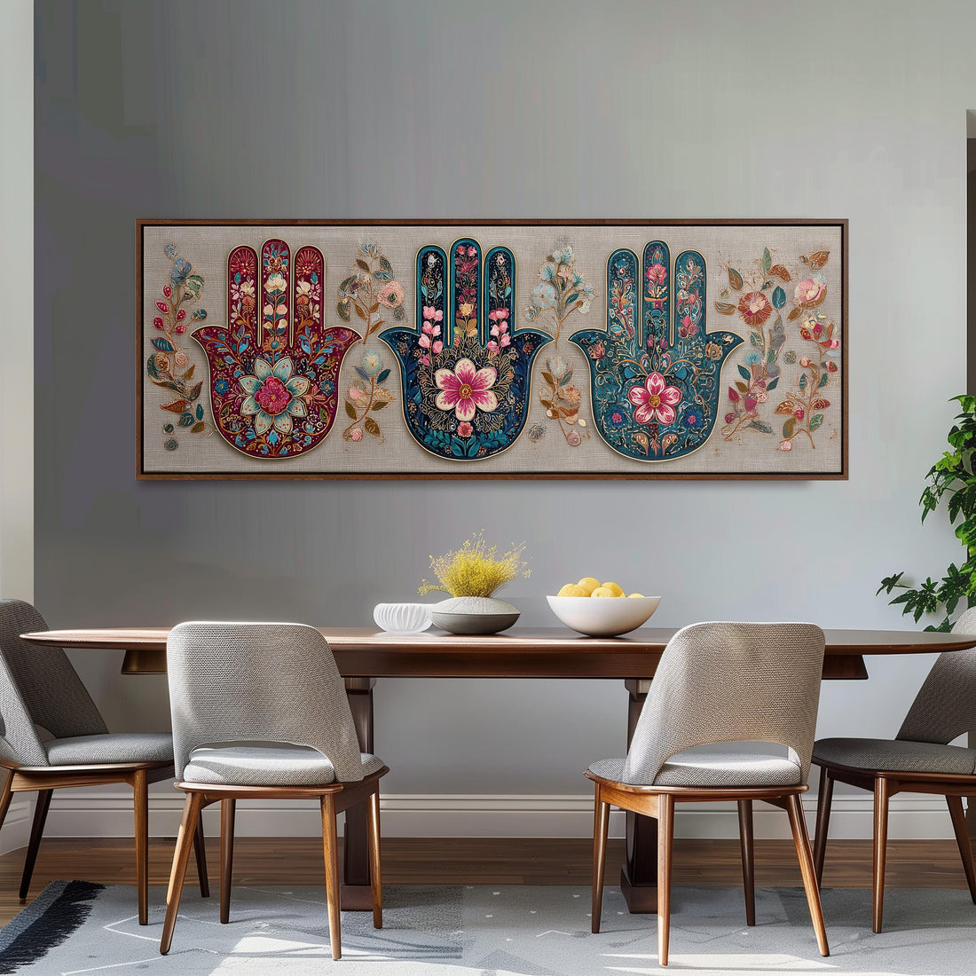 a dining room with a large, ornate, and colorful painting of three hands on the wall above a wooden dining table. The table is set with a bowl of fruit and a vase of flowers, creating a warm and inviting atmosphere.