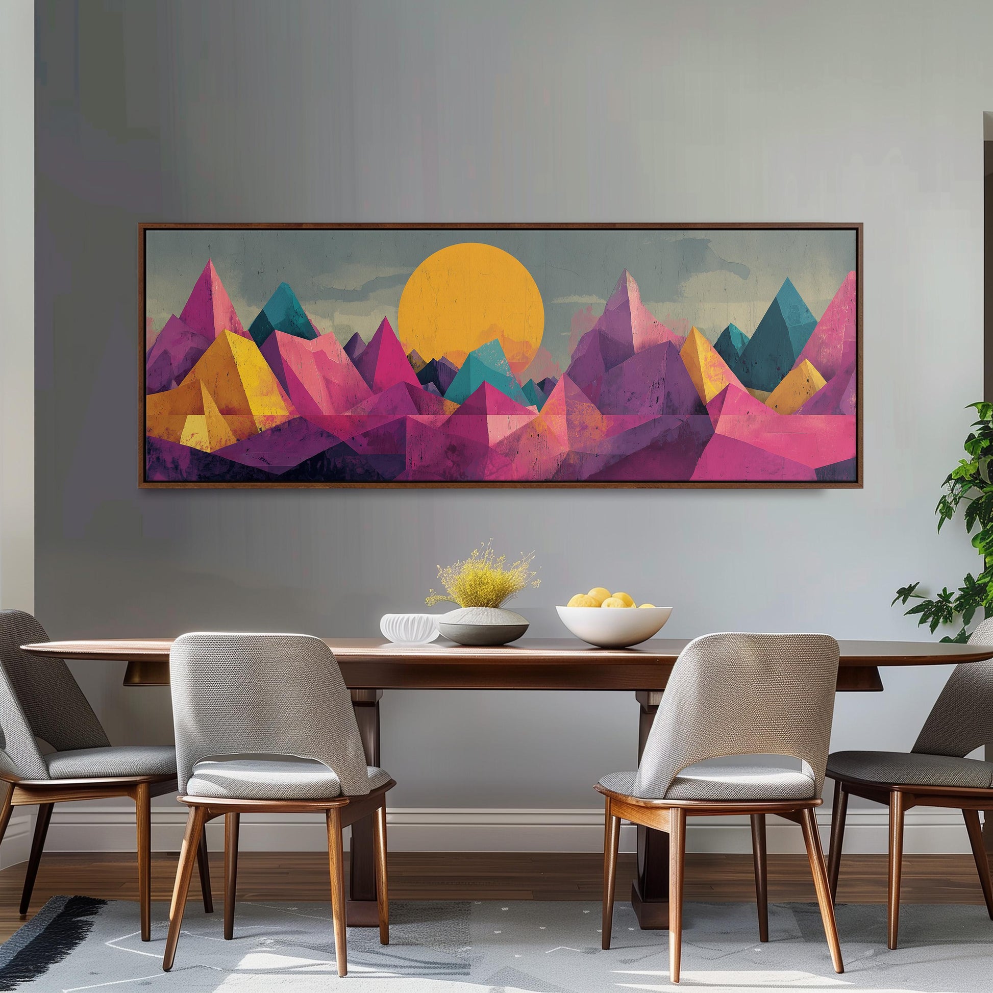 a dining room with a large, colorful painting of mountains hanging on the wall above a wooden dining table with four chairs. The painting depicts a vibrant landscape with a sun in the sky, surrounded by mountains in various shades of pink, yellow, and green.
