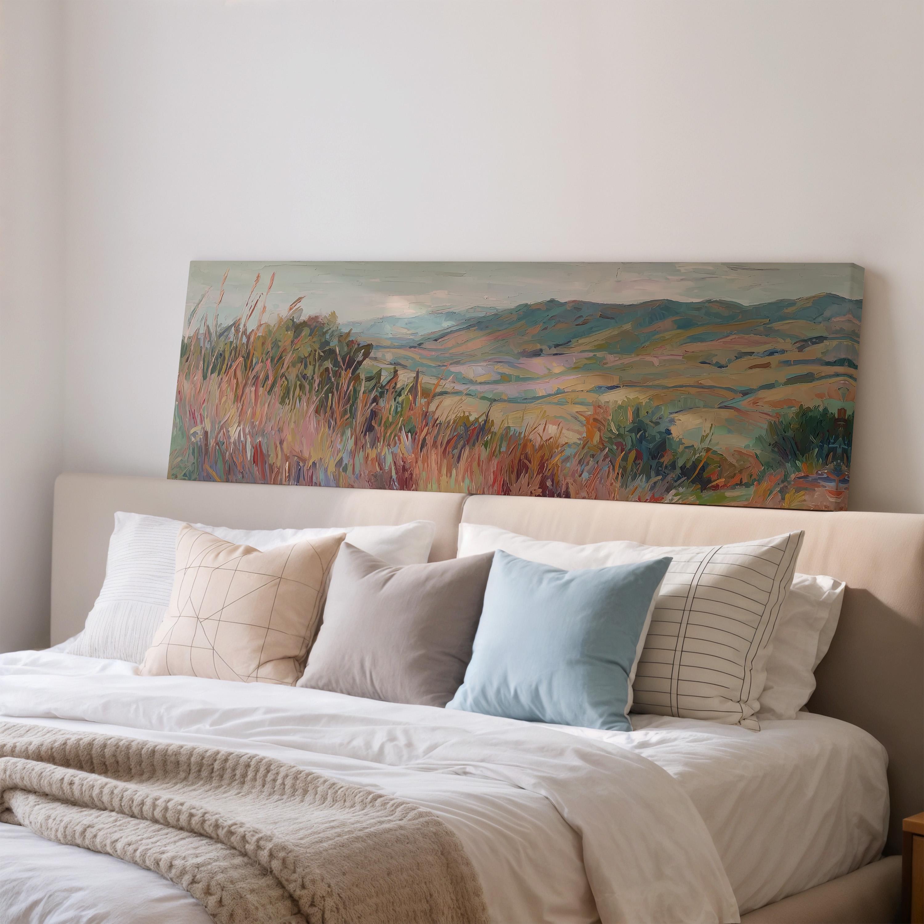 a large painting of a field with mountains in the background, hanging above a bed with white bedding and pillows.
