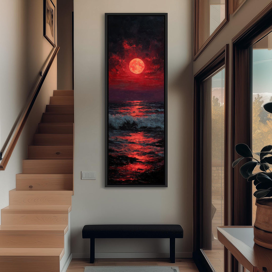 a large, framed painting of a sunset over the ocean, with a large, red moon in the sky. The painting is hanging on a wall in a hallway, with a staircase visible in the background.