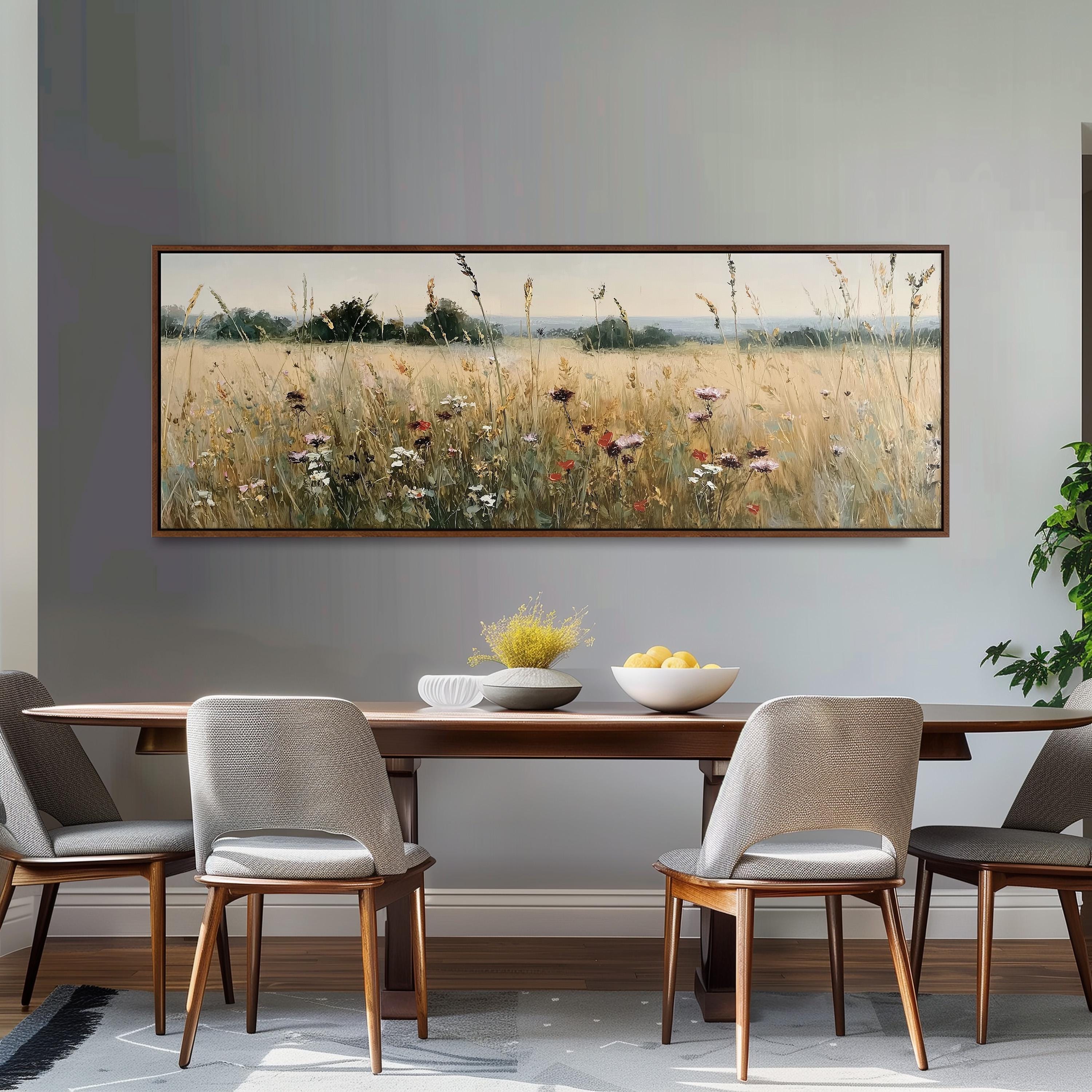 a dining room with a large painting of a field of flowers hanging on the wall above a wooden dining table with four chairs. The table is set with a bowl of fruit and a vase of flowers, creating a cozy and inviting atmosphere.