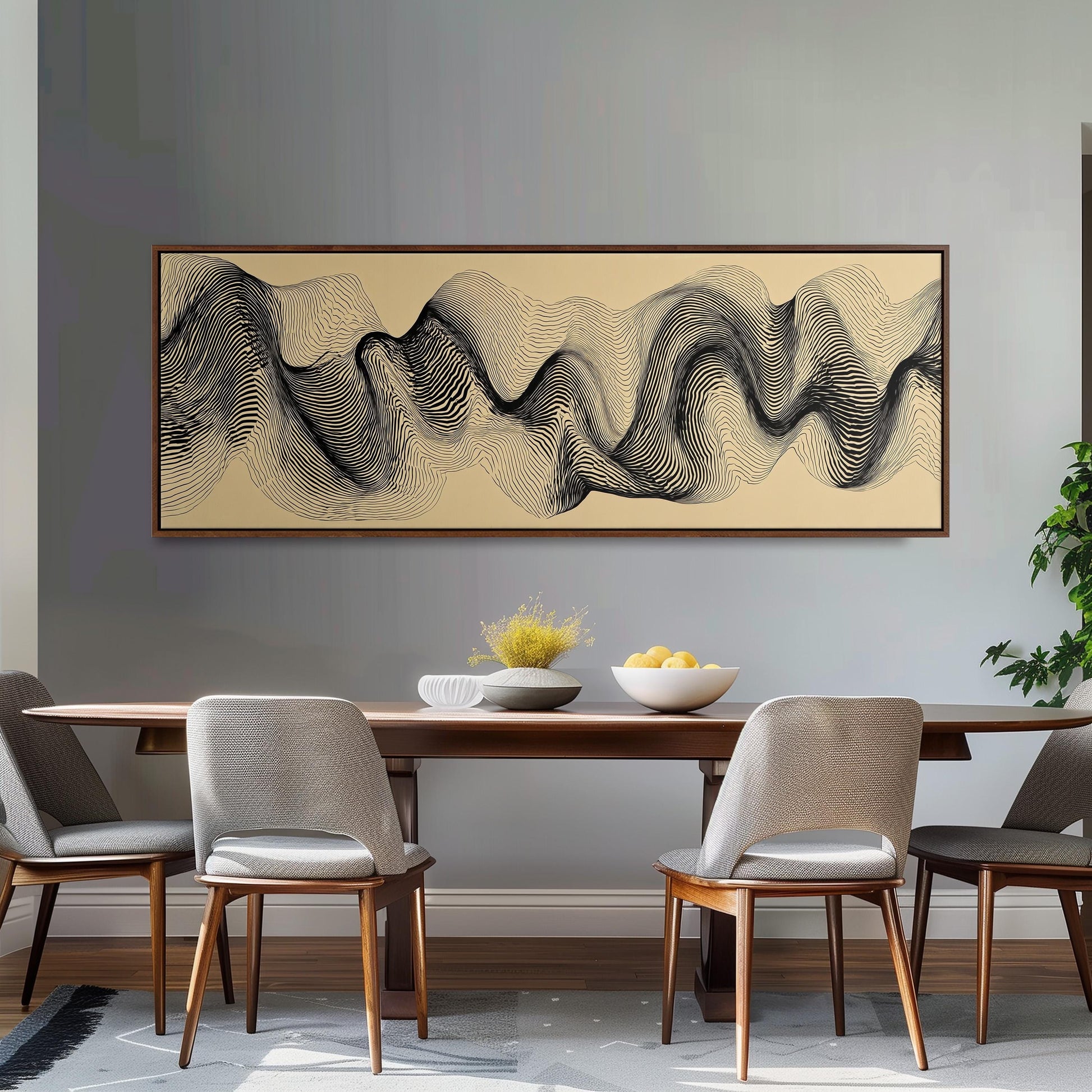 a modern dining room with a wooden table and four gray chairs. Above the table, there is a large abstract painting with a wave-like pattern in black and white. The table is set with a bowl of fruit and a vase of flowers, creating a visually appealing and inviting atmosphere.