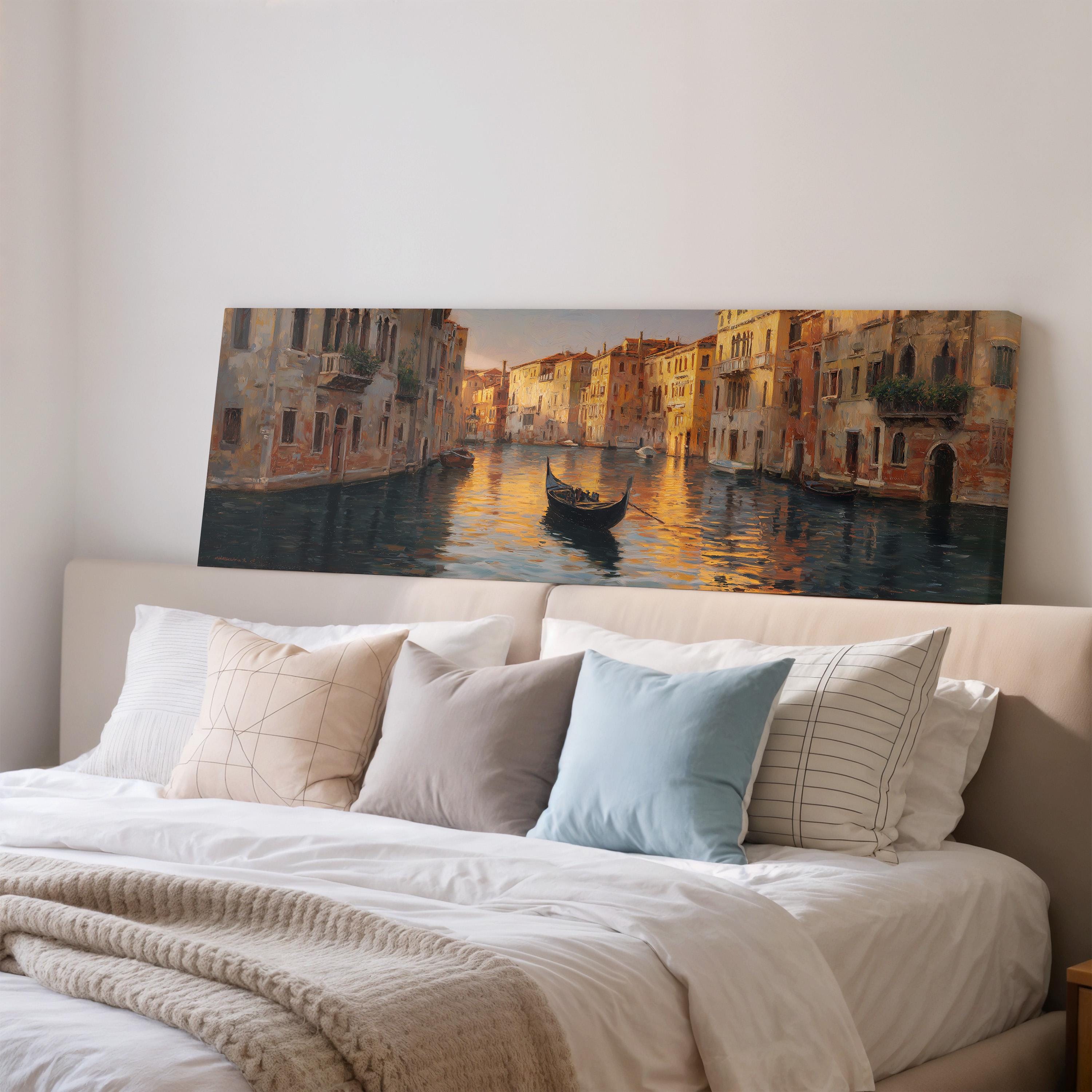 a large painting of a gondola on a canal, hanging above a bed with white pillows and a gray blanket.