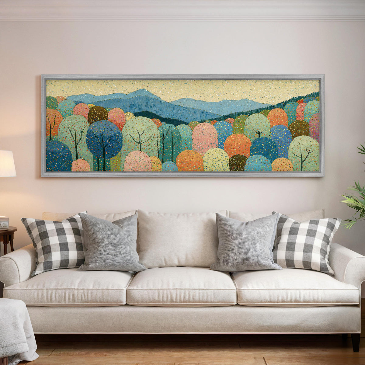 Pastel dotted forest below blue mountains panoramic canvas print above a white sofa in a bright living room