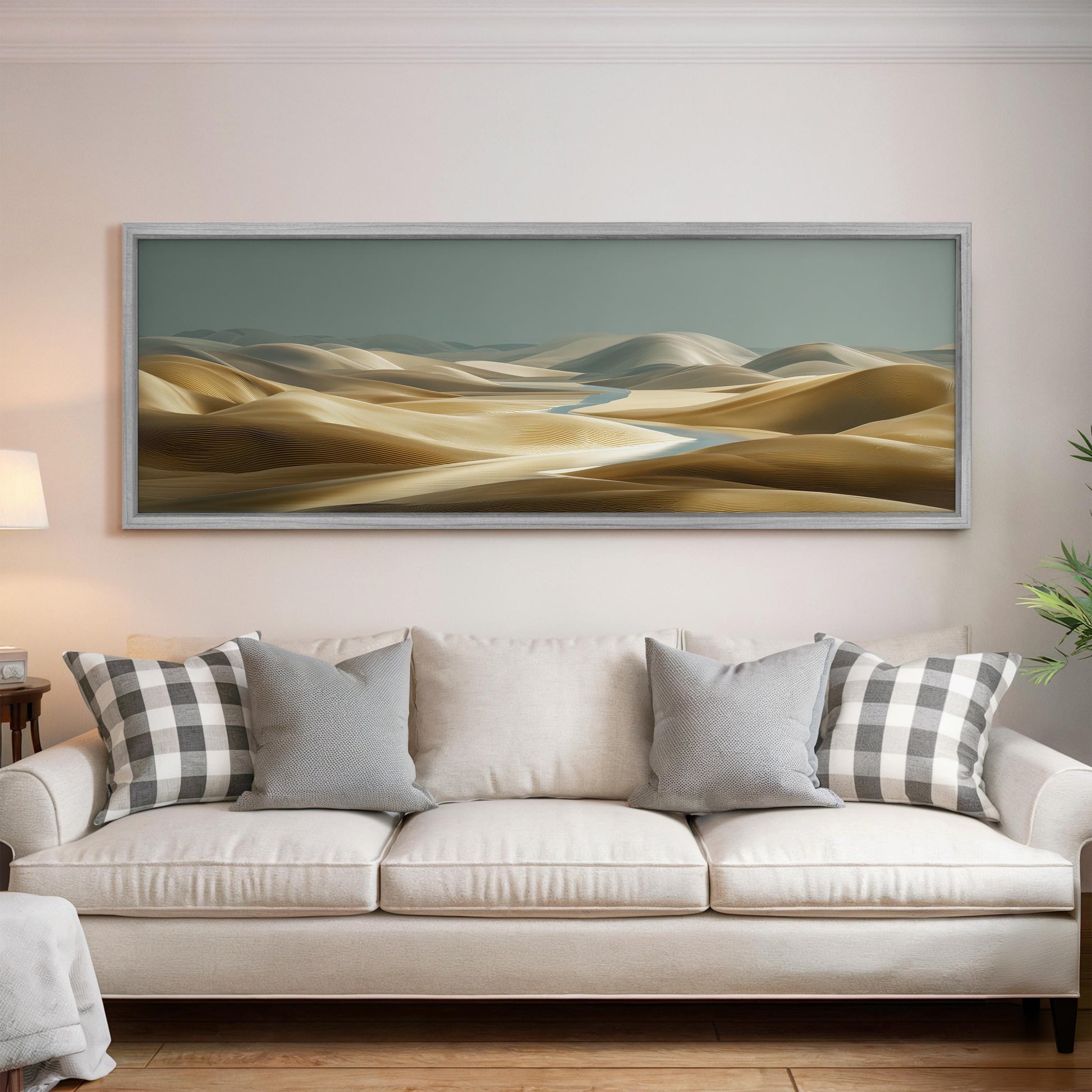a large, framed painting of a desert landscape hanging on a wall above a white sofa with patterned throw pillows.