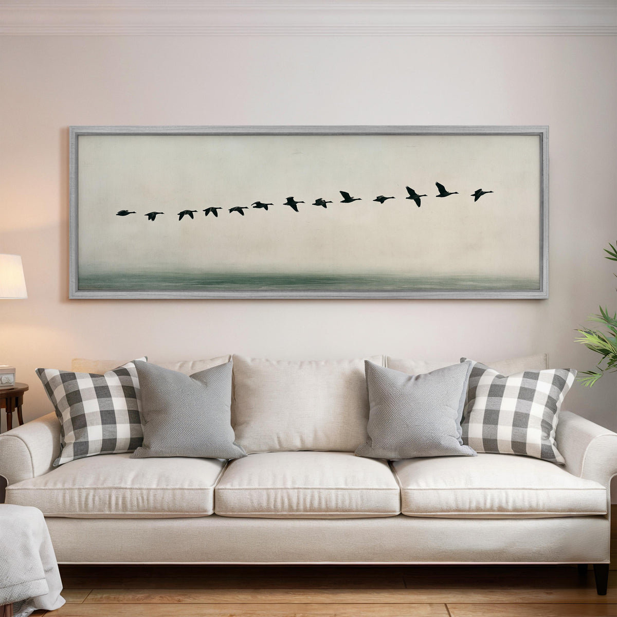 Geese flying over still water panoramic canvas print above a white sofa in a bright living room