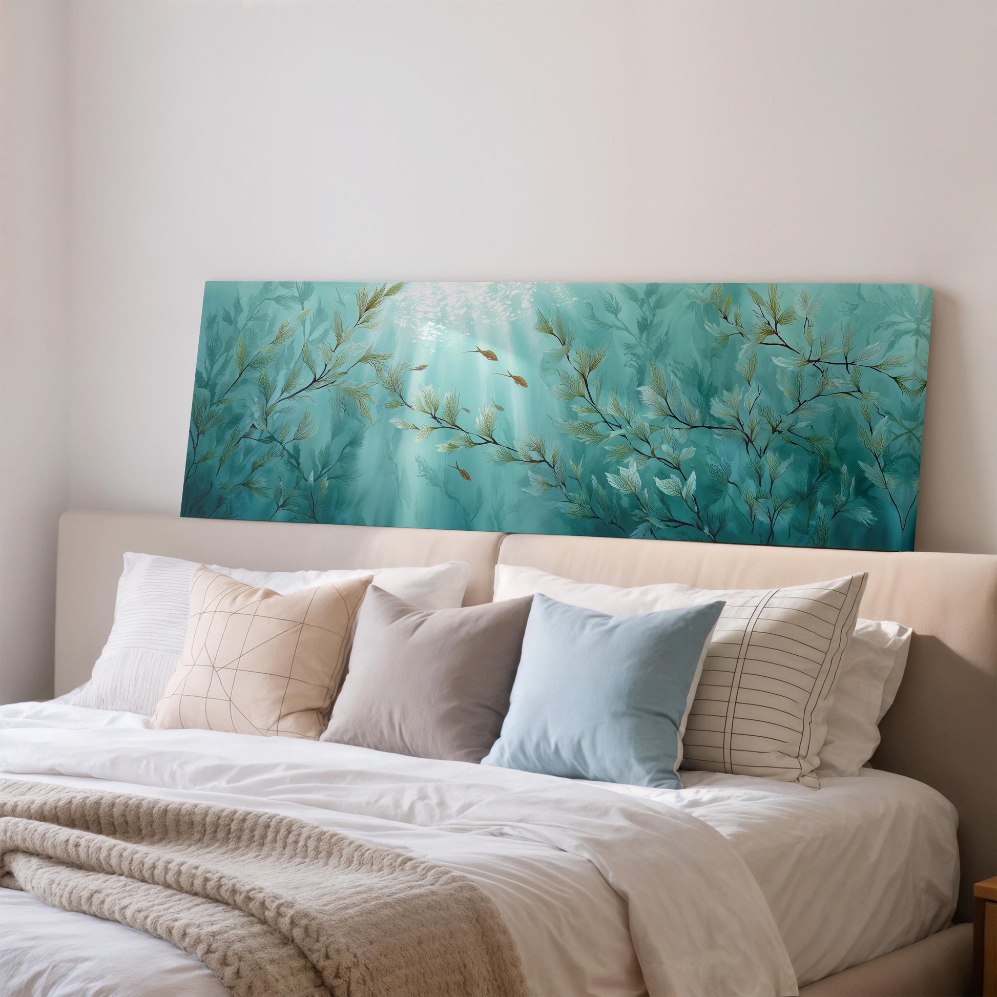 a large painting of underwater plants hanging on a wall above a bed with white pillows and a gray blanket.
