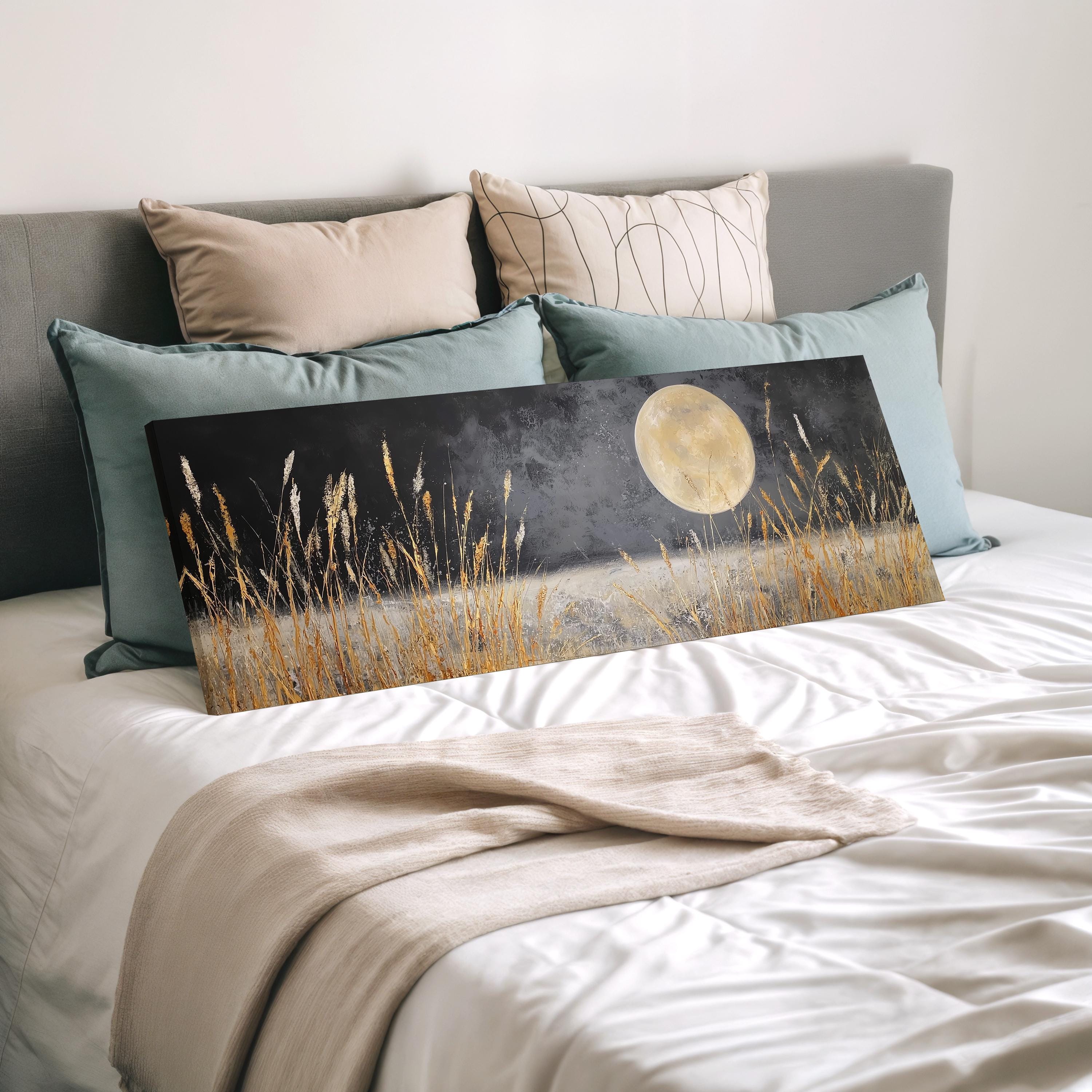 a bedroom with a bed covered in white sheets and a large painting of a field with tall grass and a full moon on the bed.