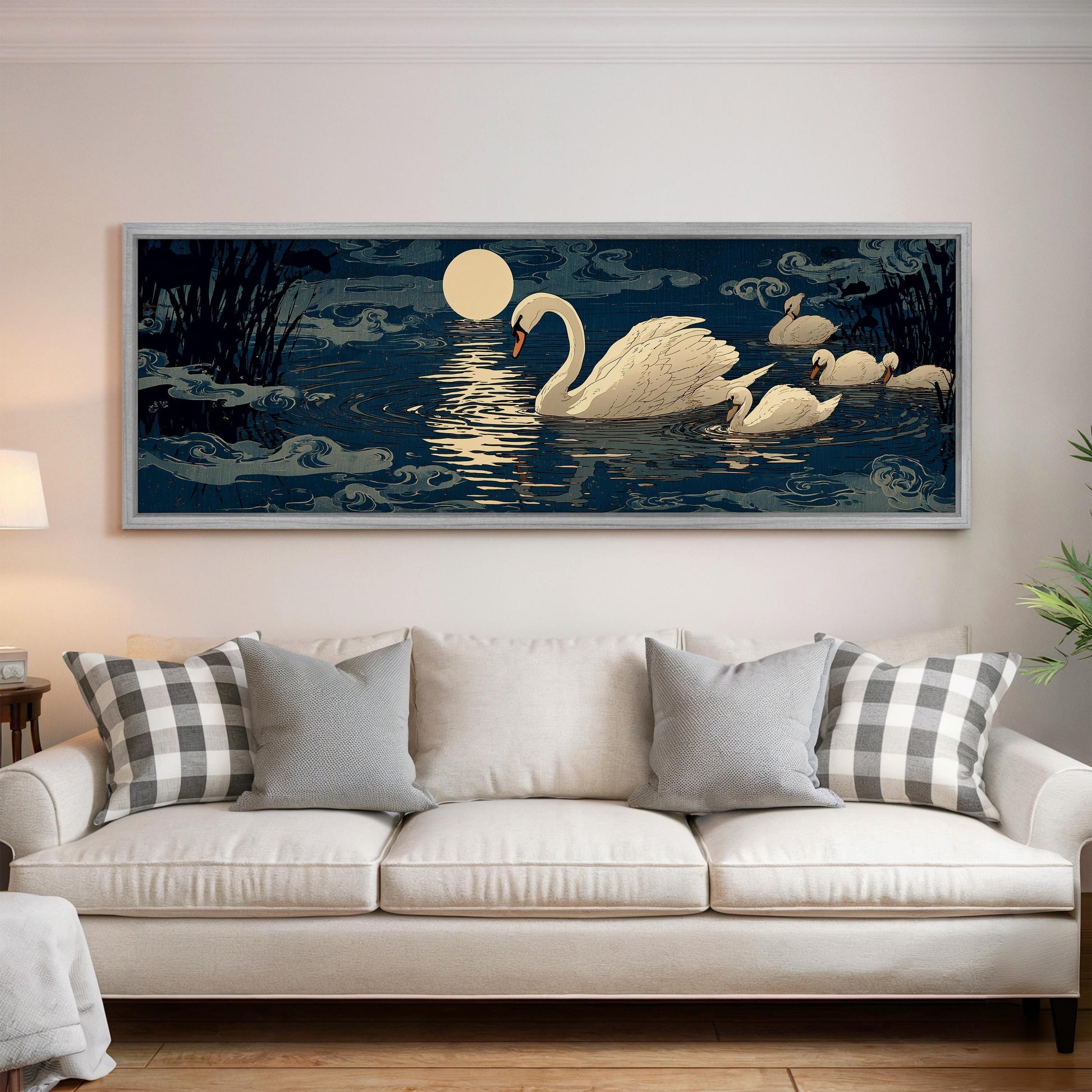 A large framed painting depicting a serene scene of swans swimming on a lake at night, with a full moon and clouds in the background.