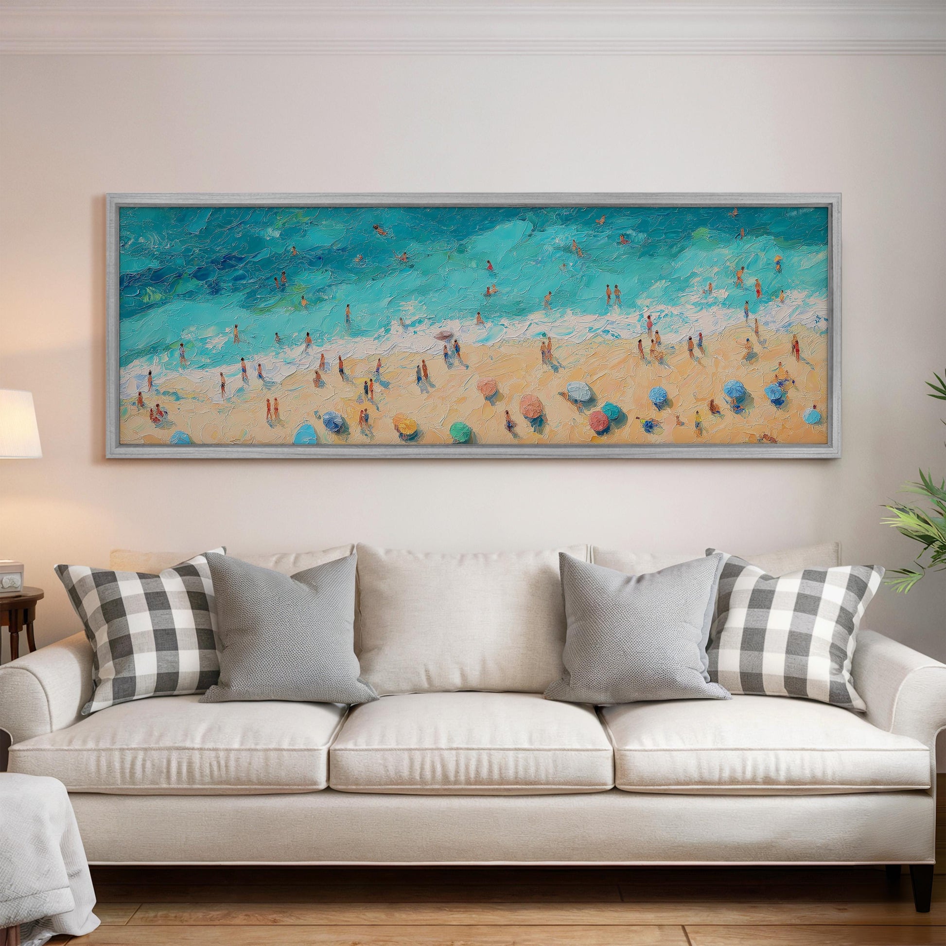 a large painting of a beach scene hanging on a wall above a white couch with gray and white patterned pillows.