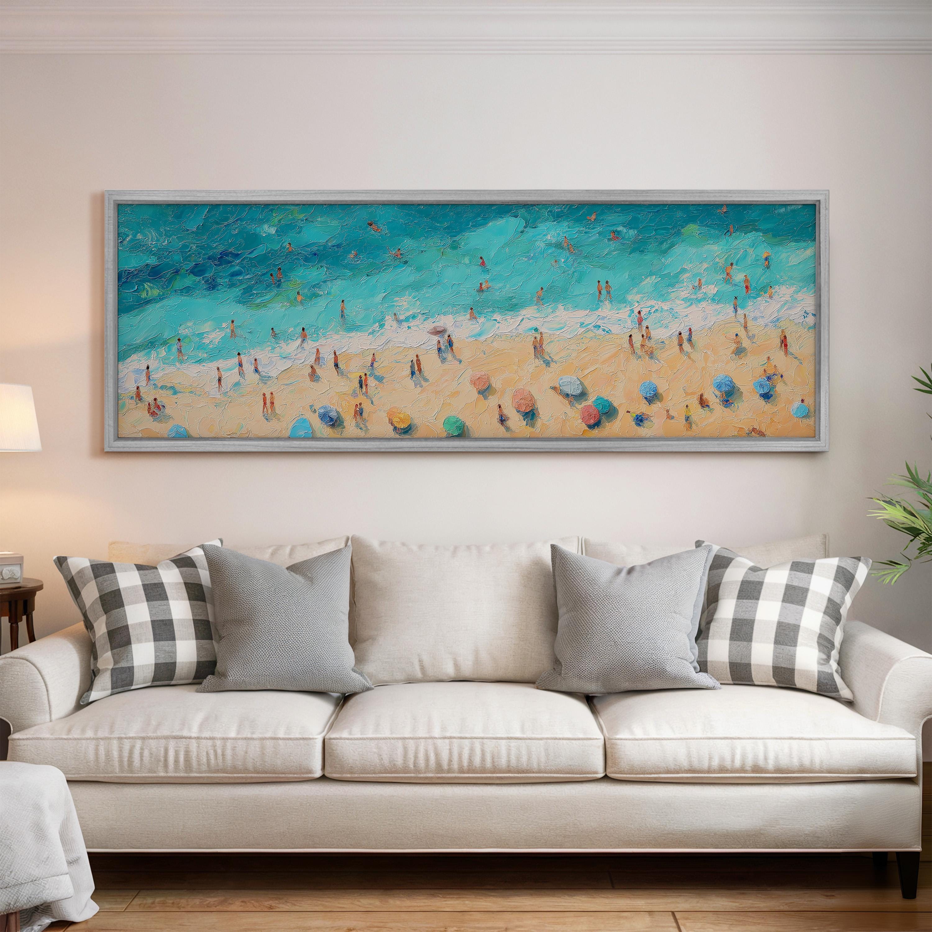 a large painting of a beach scene hanging on a wall above a white couch with gray and white patterned pillows.