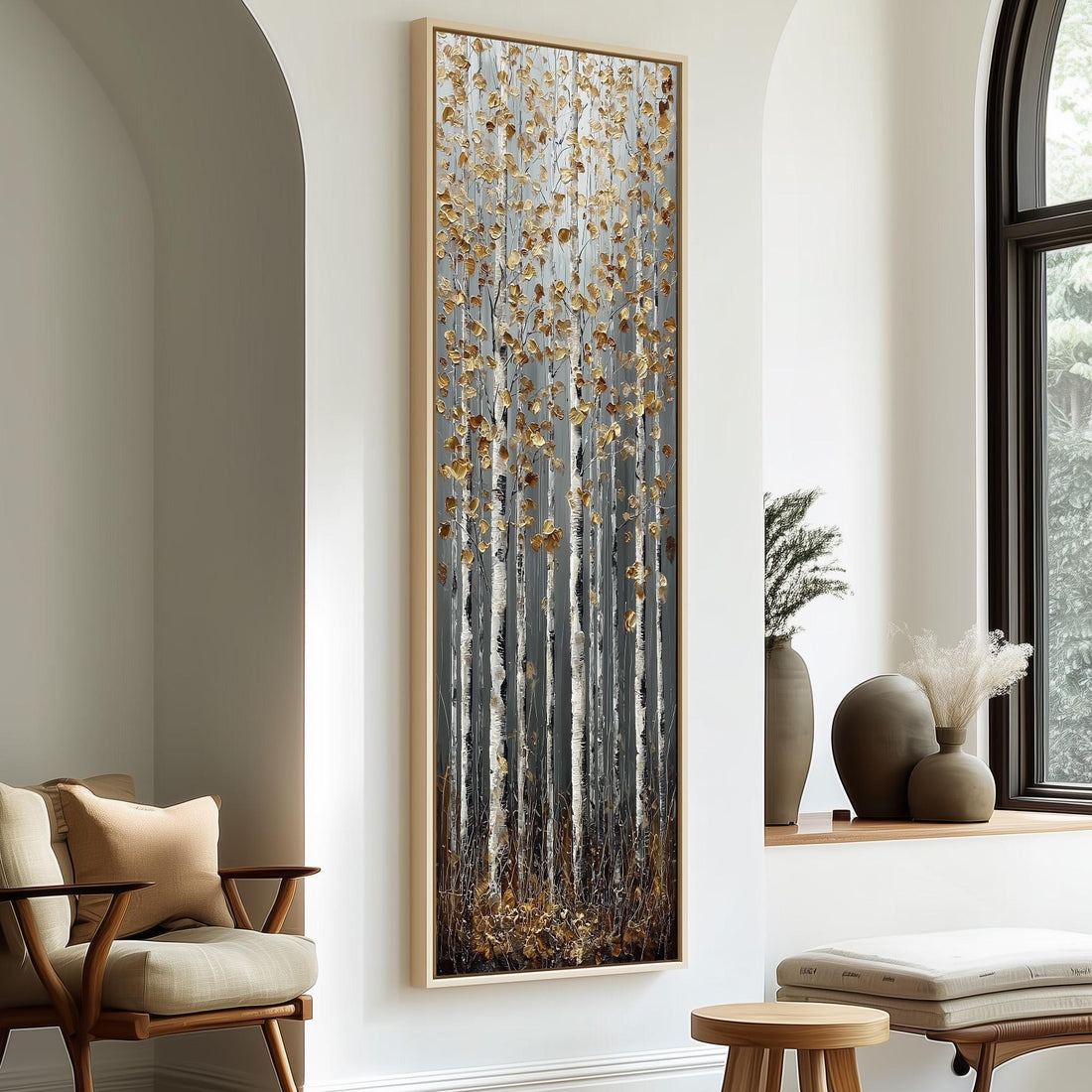 a large, framed painting of a forest scene with tall trees and a mix of brown and white colors. The painting is hanging on a white wall, and there are two chairs and a small table in the foreground.