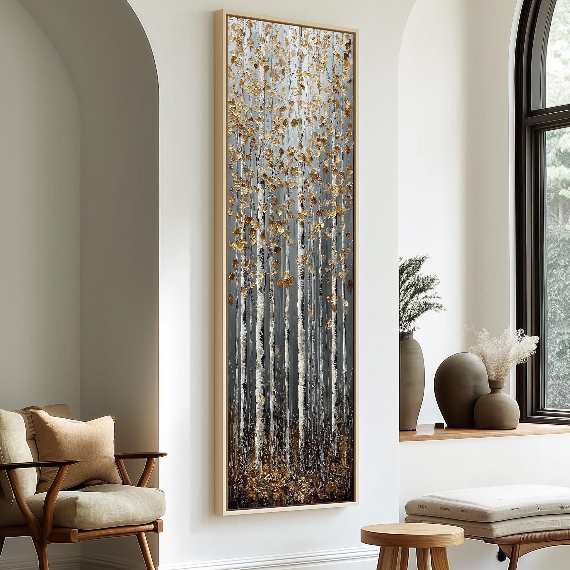 a large, framed painting of a forest scene with tall trees and a mix of brown and white colors. The painting is hanging on a white wall, and there are two chairs and a small table in the foreground.