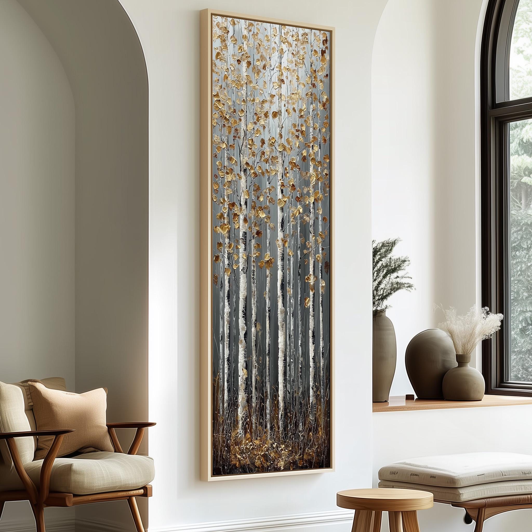 a large, framed painting of a forest scene with tall trees and a mix of brown and white colors. The painting is hanging on a white wall, and there are two chairs and a small table in the foreground.