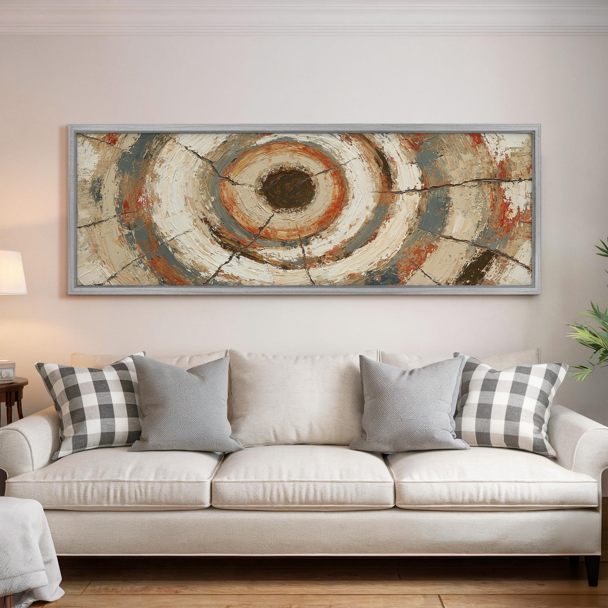 Rust and navy textured tree ring panoramic canvas print above a white sofa in a bright living room