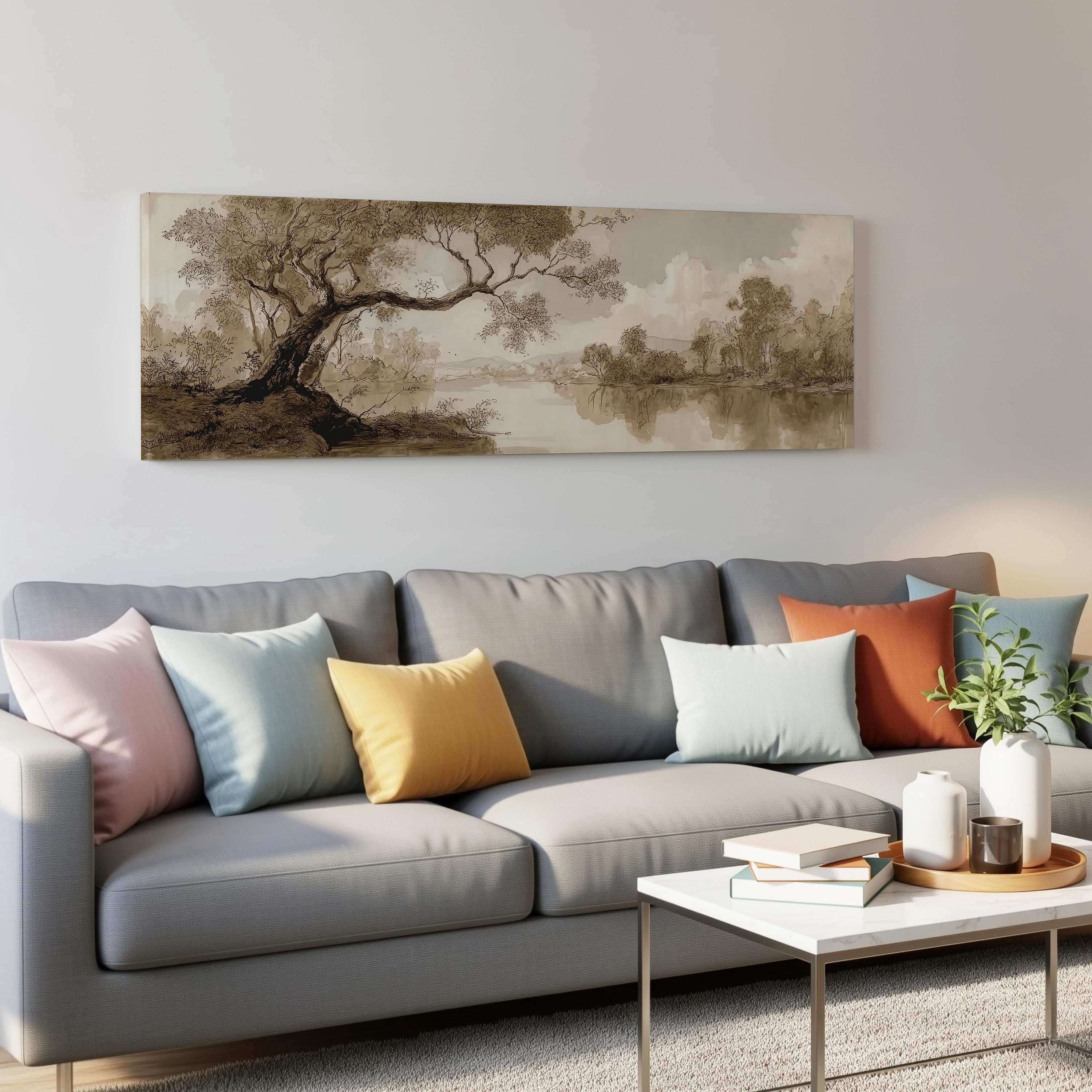 a living room with a gray sofa adorned with colorful throw pillows, a coffee table with books and a plant, and a large landscape painting hanging on the wall above the sofa.