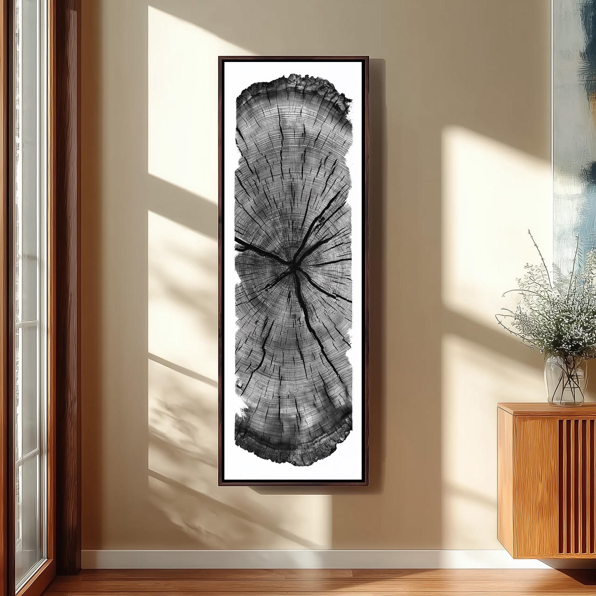 a large, vertical framed artwork depicting a cross-section of a tree trunk, mounted on a wall in a room with a wooden floor and a window.