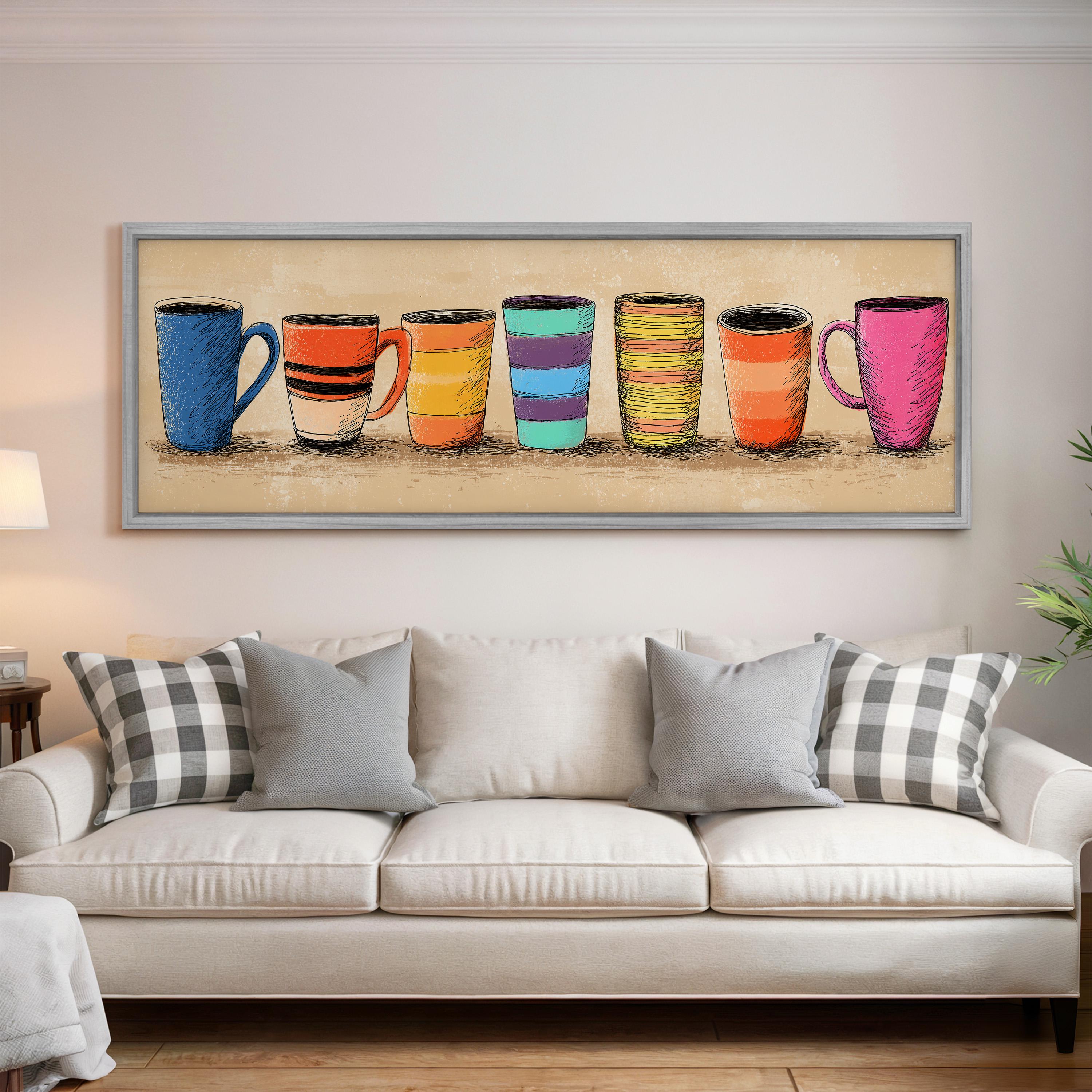 a large framed artwork depicting a row of colorful mugs on a wall above a white couch with gray and black plaid throw pillows.
