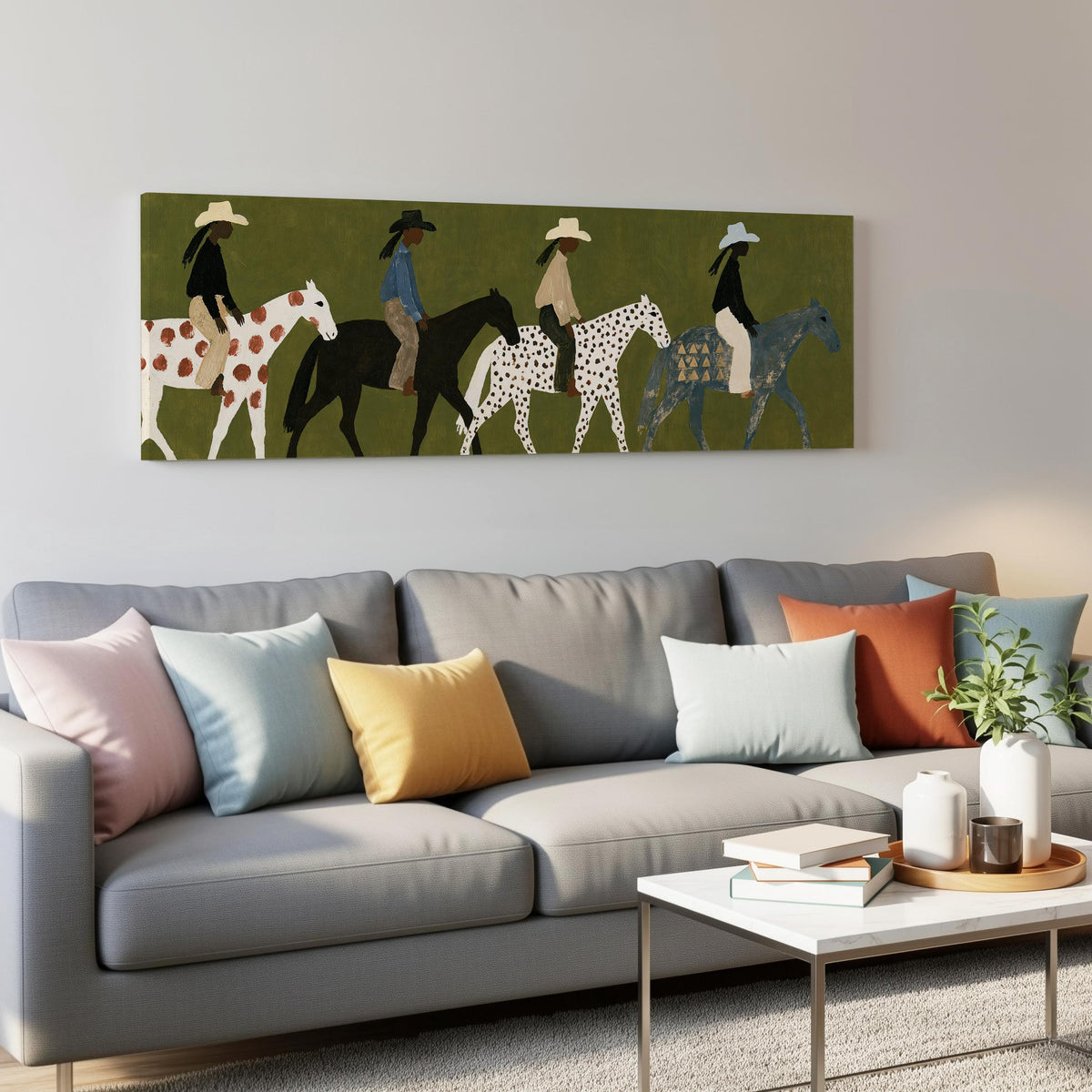 Riders on spotted ponies on olive green panoramic canvas print above a grey sofa in a living room
