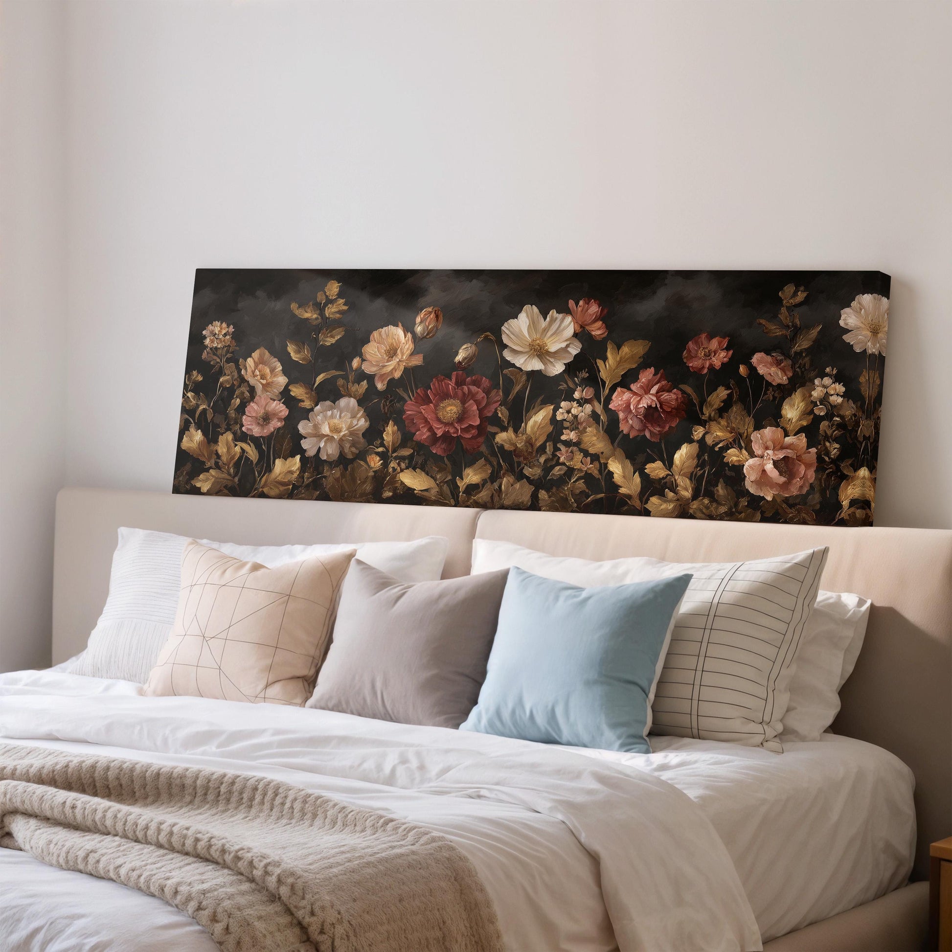 a large floral painting hanging on a wall above a bed with white pillows and a gray blanket.