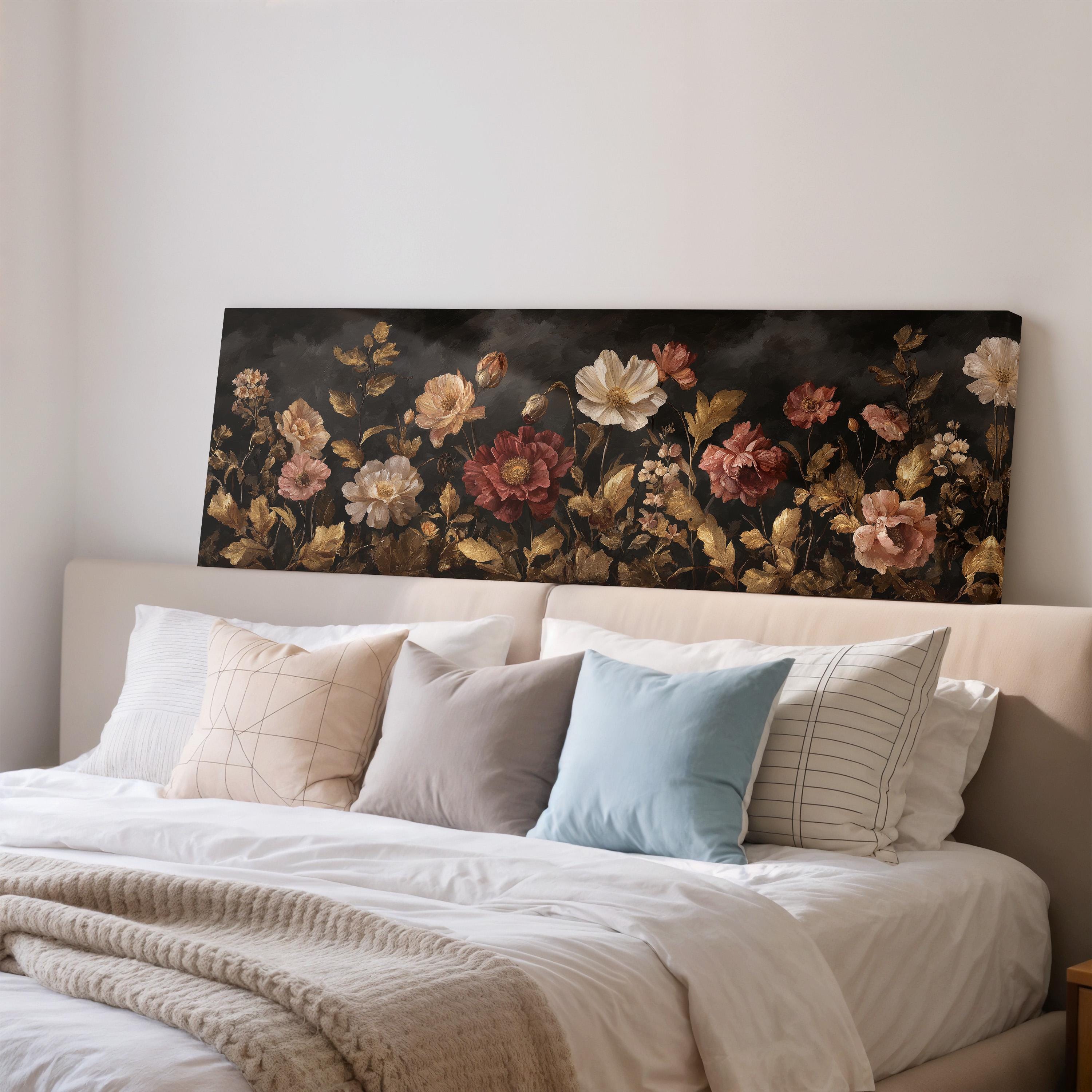 a large floral painting hanging on a wall above a bed with white pillows and a gray blanket.