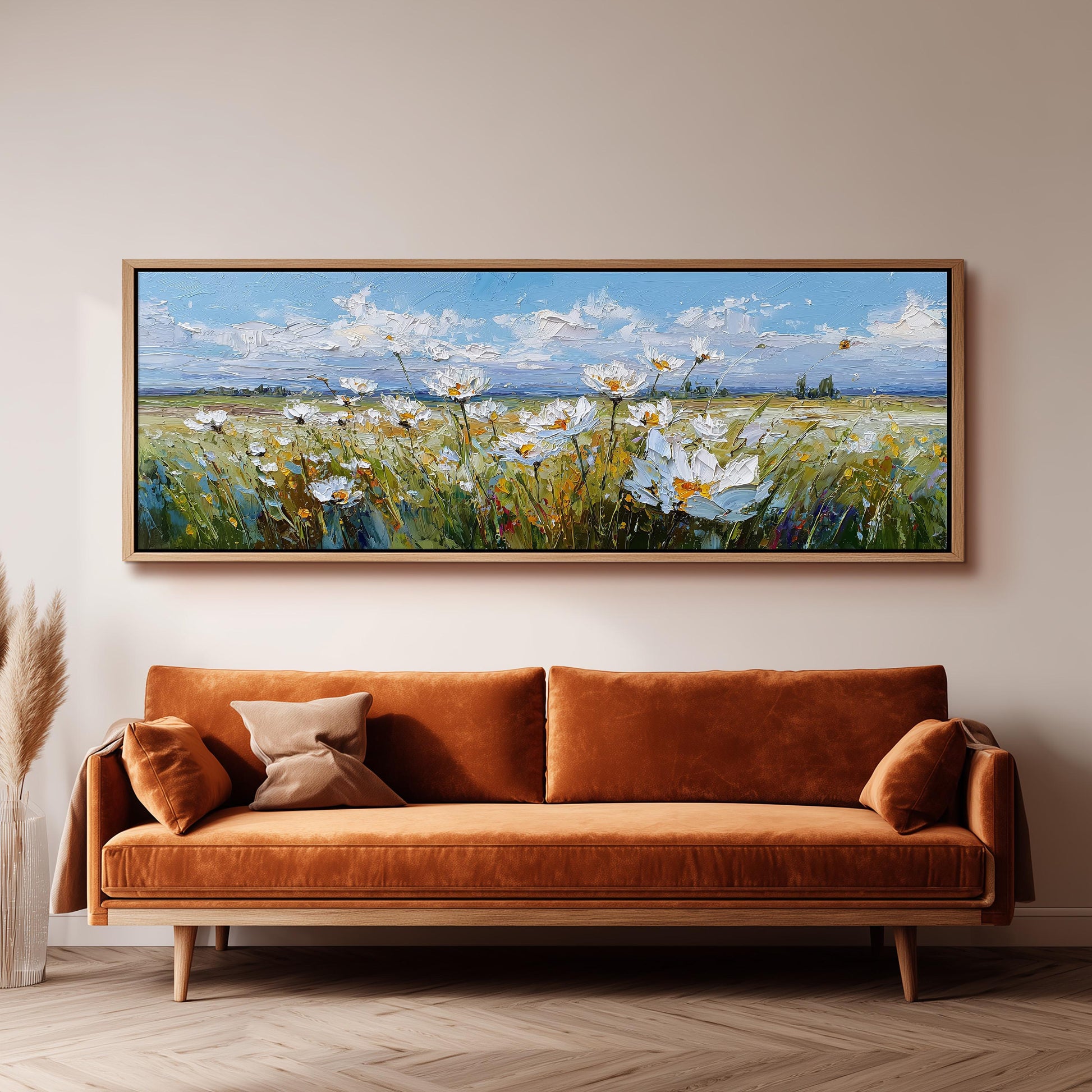 a large painting of a field of flowers hanging on a wall above a brown sofa.