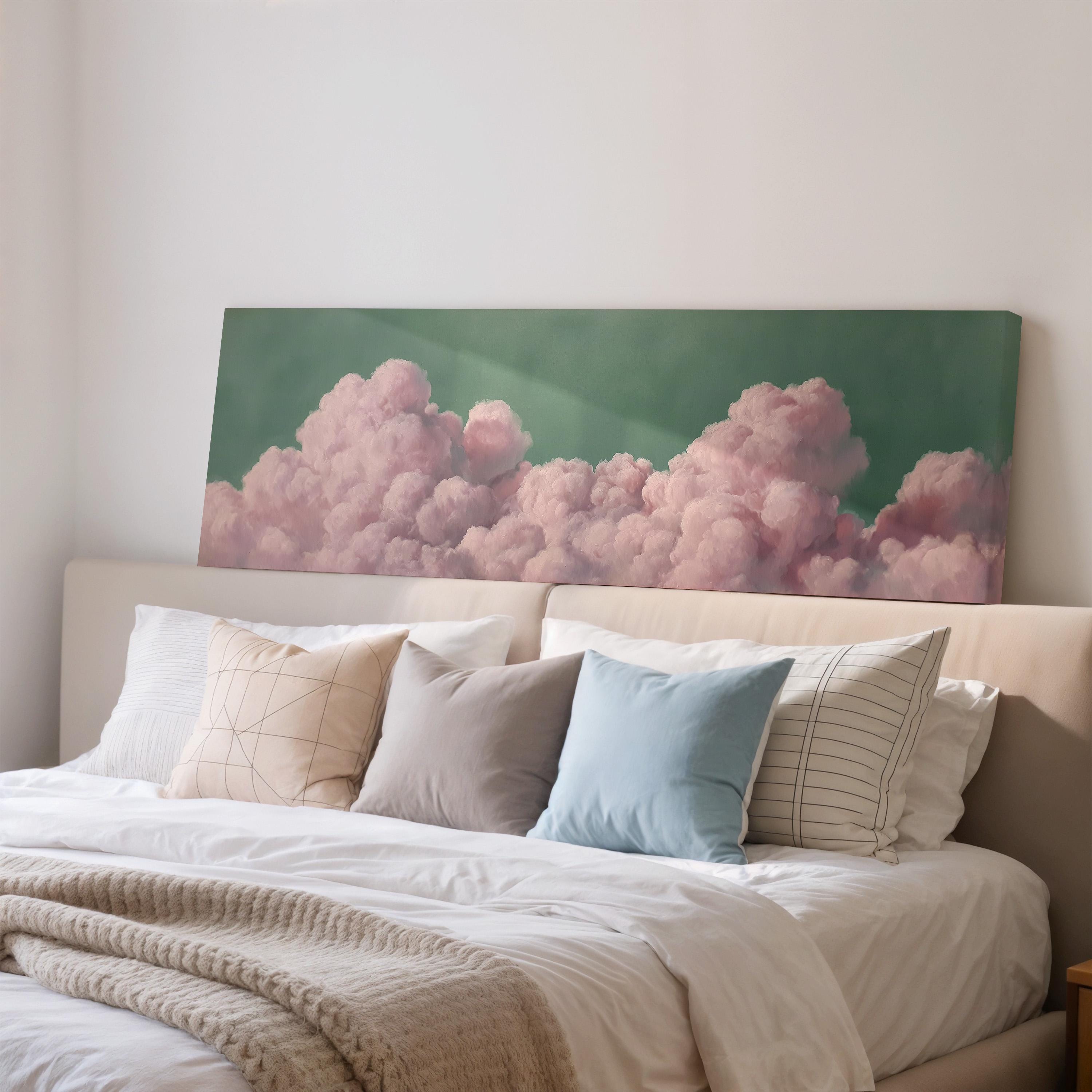 a large bed with white sheets and pillows, and a large canvas print of pink clouds hanging above it.