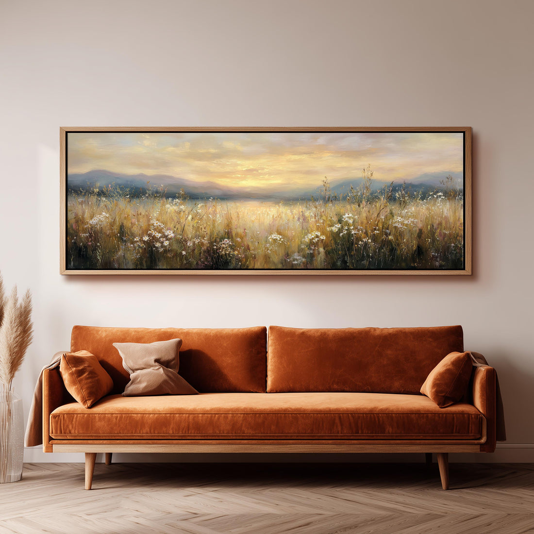 a large, framed painting of a field with flowers hanging on a wall above a brown sofa.