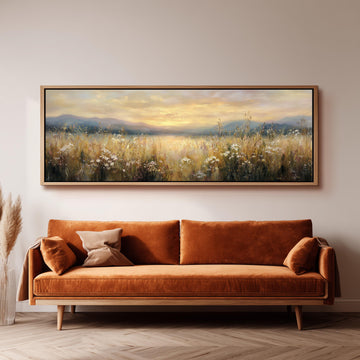 a large, framed painting of a field with flowers hanging on a wall above a brown sofa.