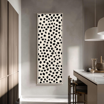 a modern kitchen with a large black and white abstract painting hanging on the wall. The painting has a repeating pattern of black dots on a white background, creating a striking visual contrast. The kitchen is equipped with a white countertop and a wooden cabinet, and there are two chairs placed in front of the countertop.