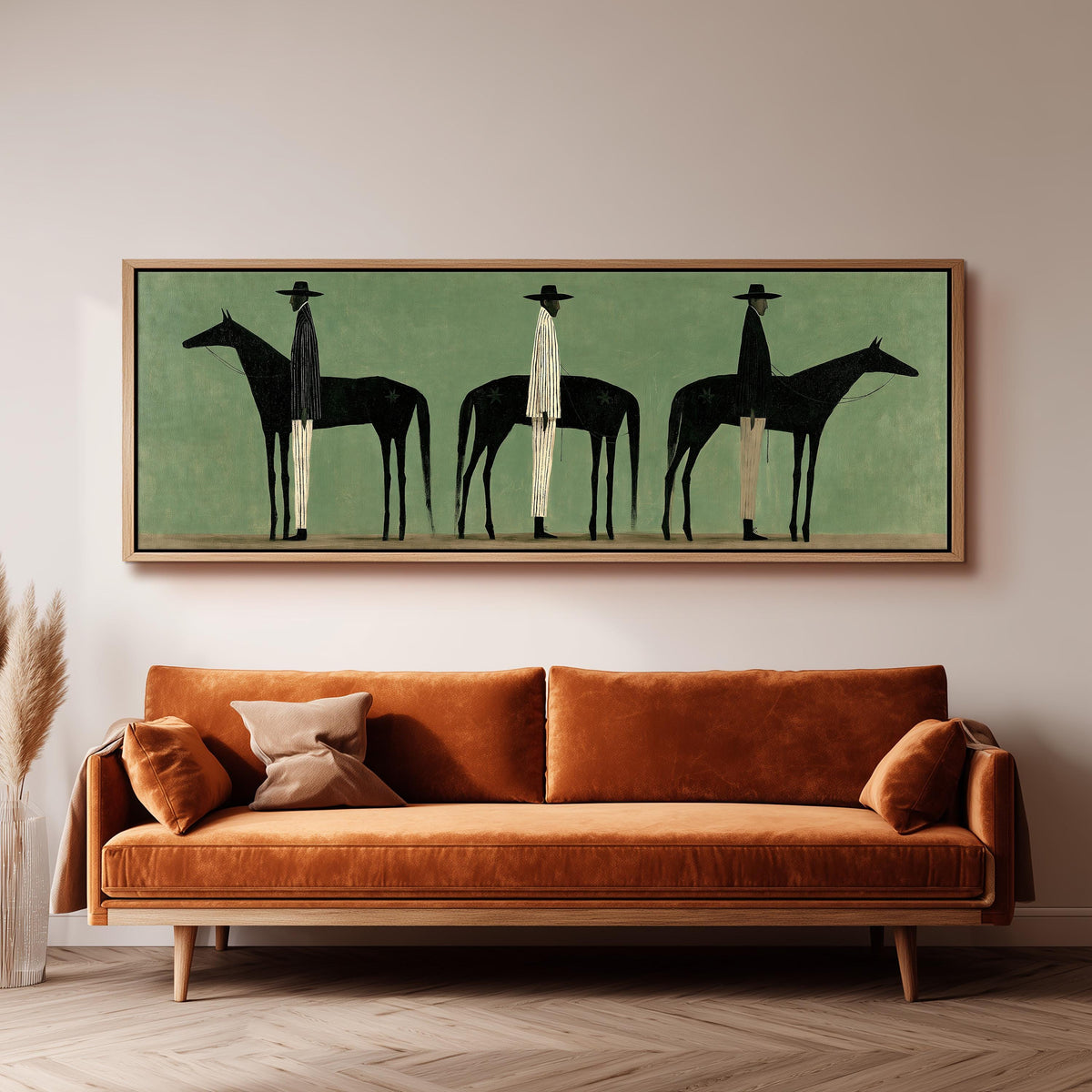 Three stylized cowboys with horses on sage green panoramic canvas print above a sofa in a living room