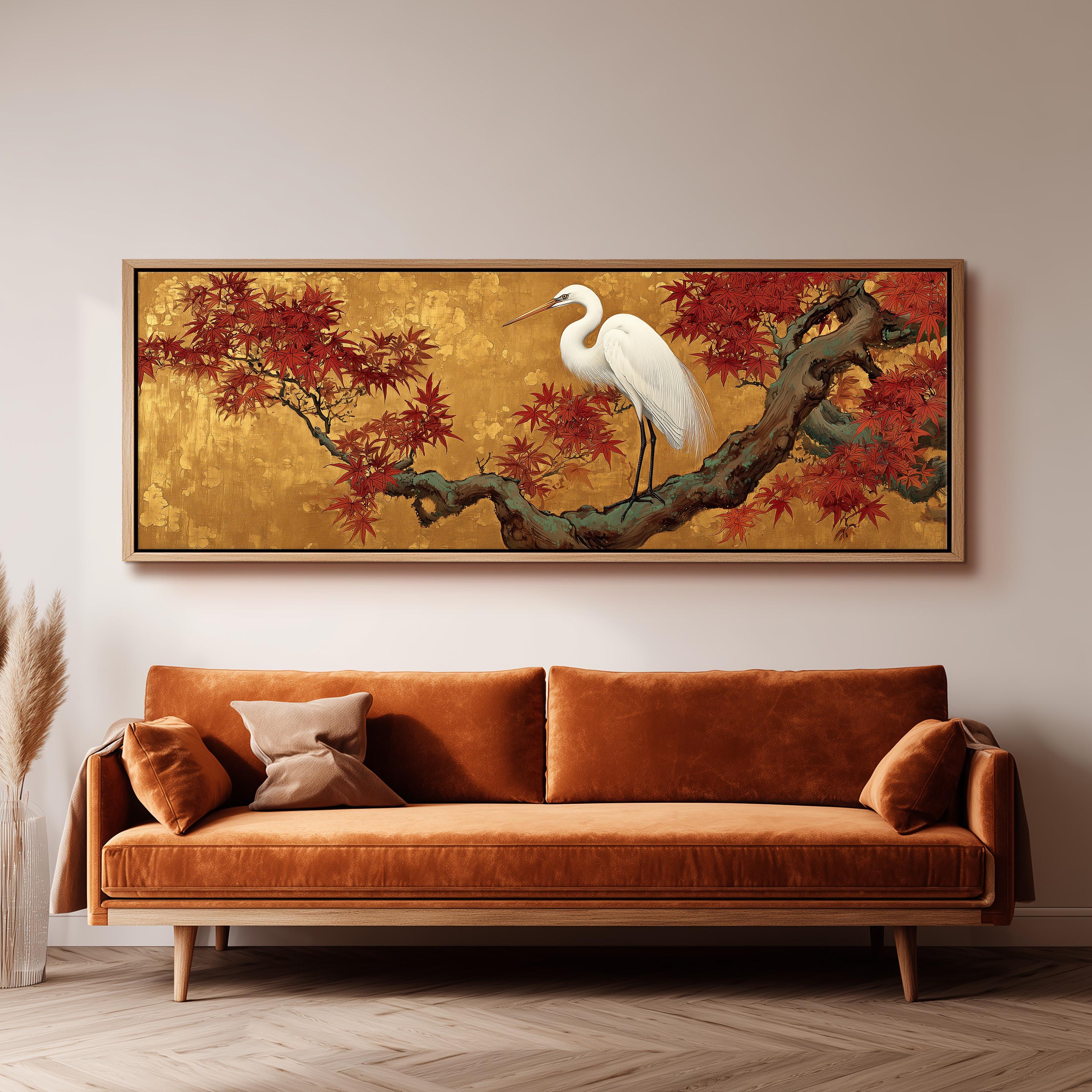 a large, framed painting of a white crane standing on a branch with red leaves, hanging on a wall above a brown sofa.