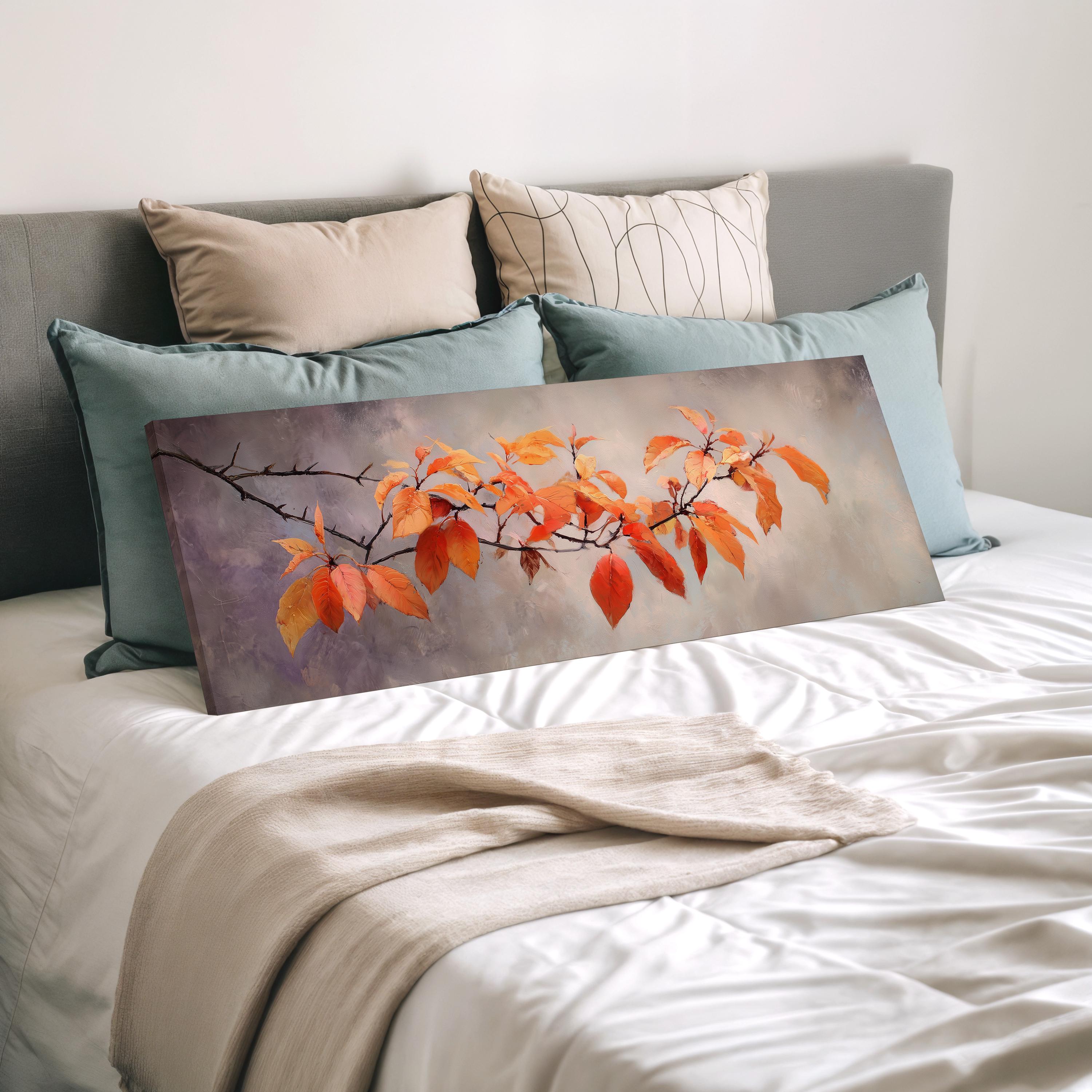 a bedroom with a bed and a painting of orange leaves on the bed. The painting is placed on a white bedspread, and there are several pillows surrounding it.