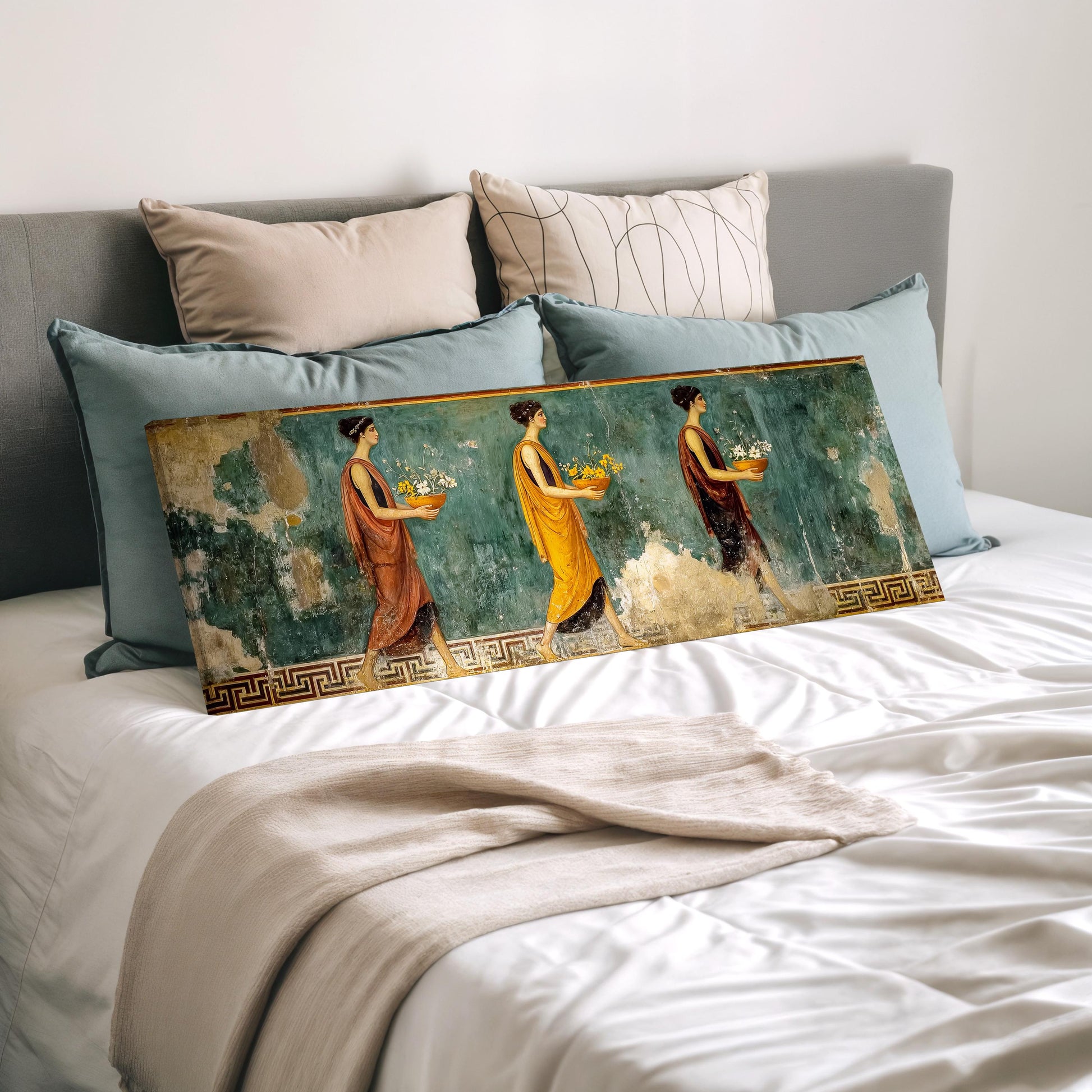 a large painting of three women, each holding a different object, displayed on a bed with pillows.