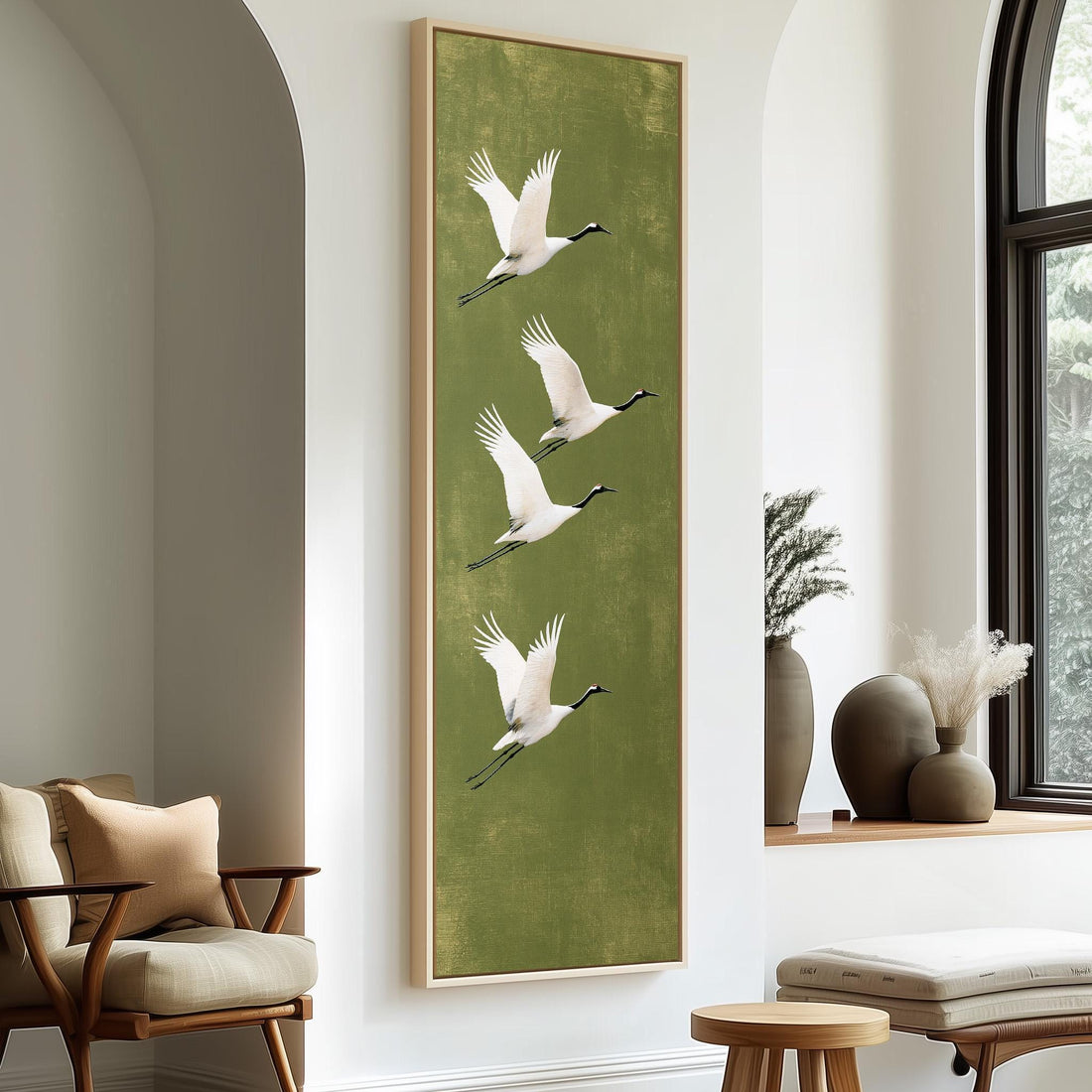 Four white cranes flying on olive green long vertical canvas print in a sunlit living space
