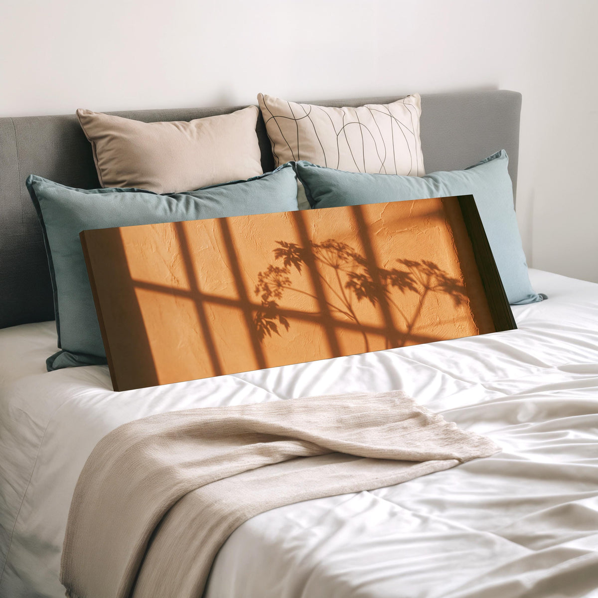 Plant and window shadows on a terracotta wall wide panoramic canvas print laid on a bed to show its size