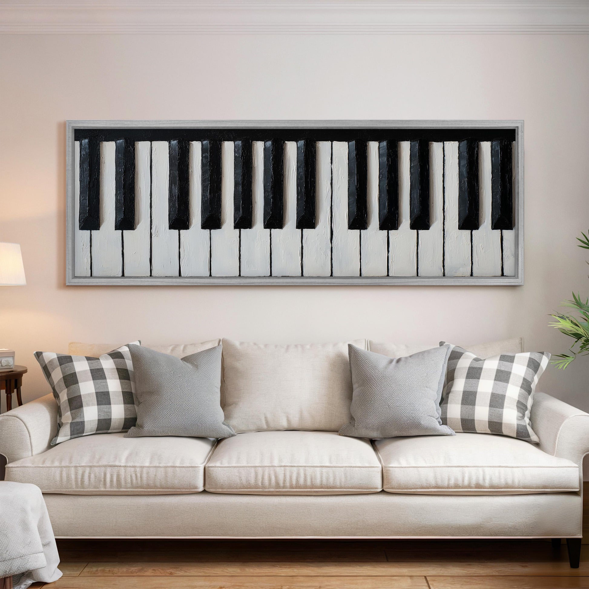 a large framed painting of a piano keyboard hanging on a wall above a white couch with gray and white pillows.